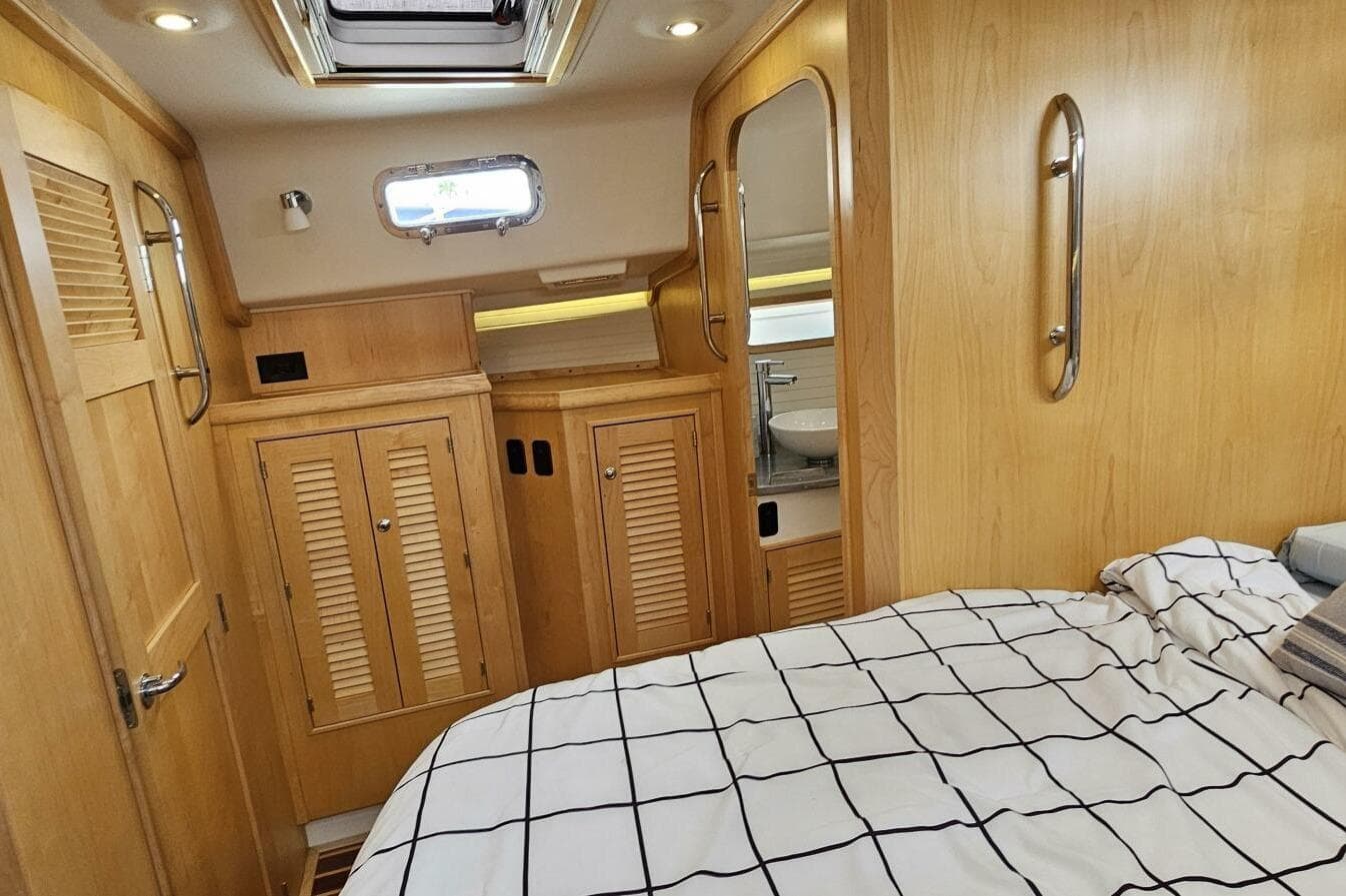 2023 Island Packet 439 yacht interior with wooden cabinetry and cozy bedding.