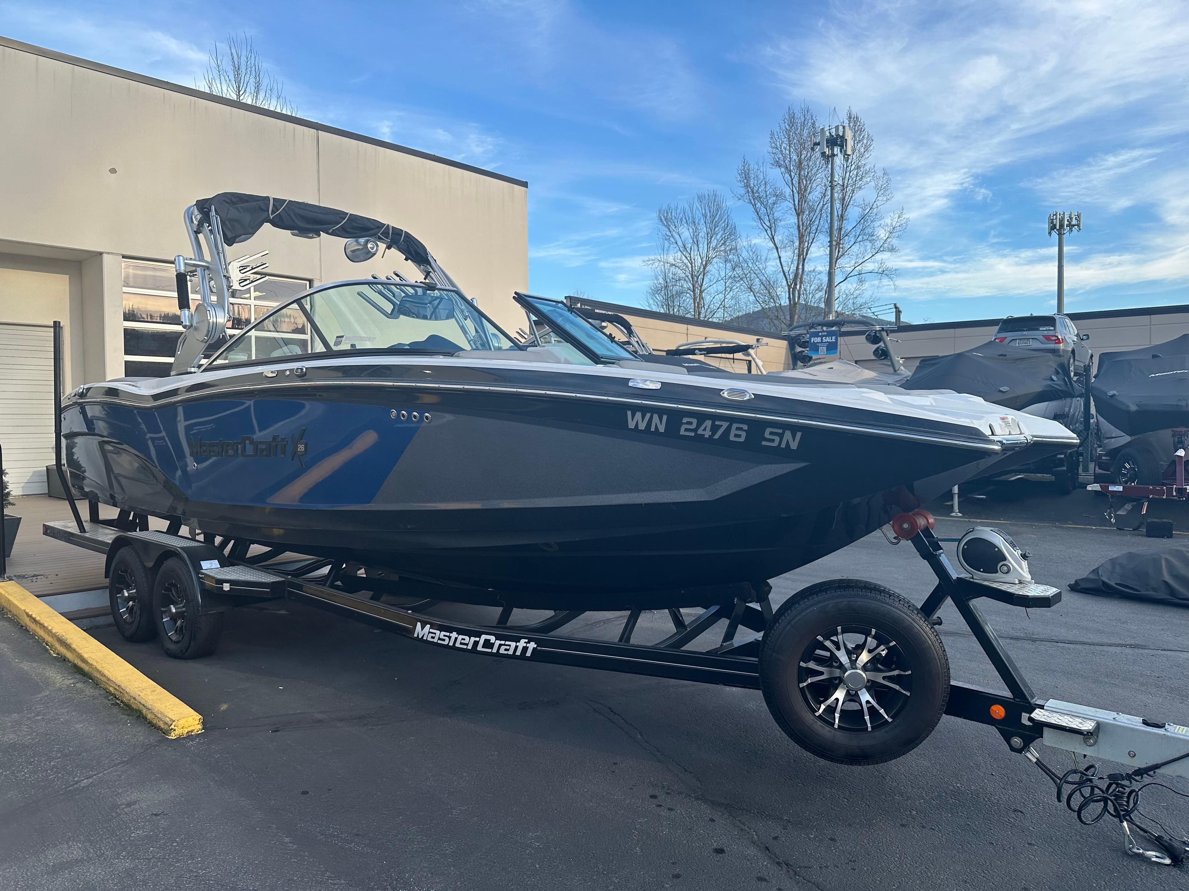 2017 MasterCraft X26 boat on trailer, parked outdoors, with blue and gray design.