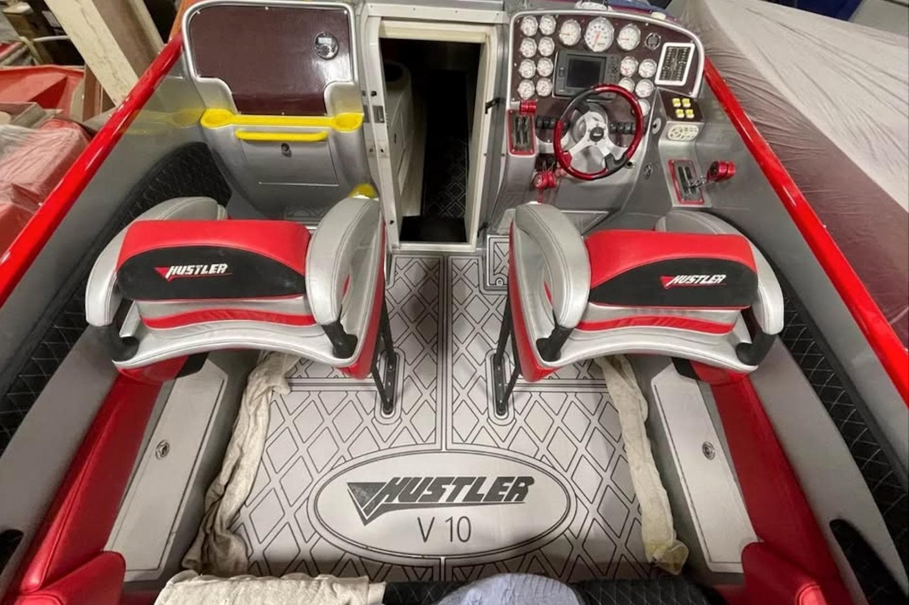 2005 Hustler 388 SLINGSHOT boat interior with red and gray seating, dashboard, and controls.