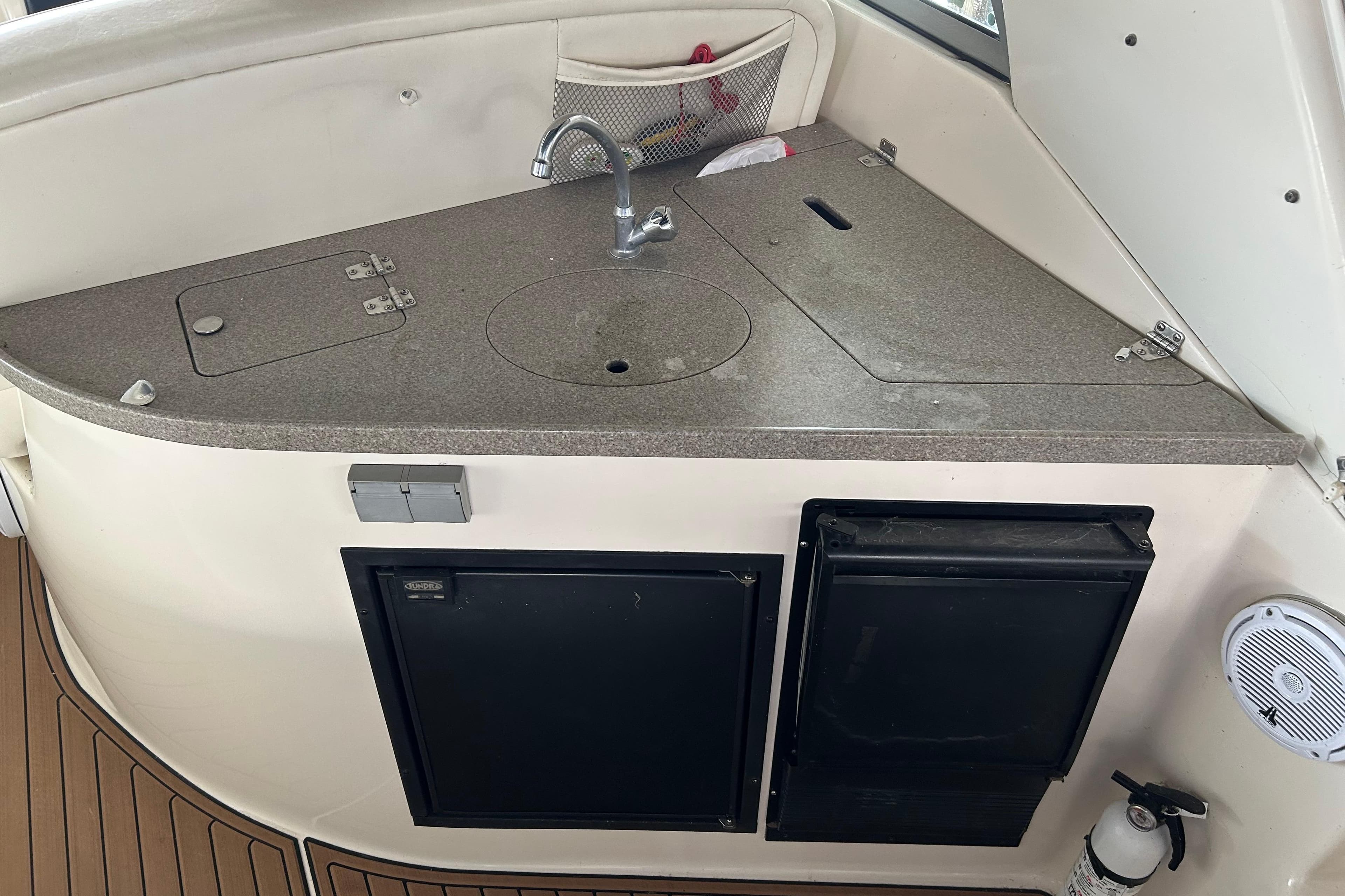 2003 Rinker 342 Express Cruiser kitchenette with sink, storage, and appliances.