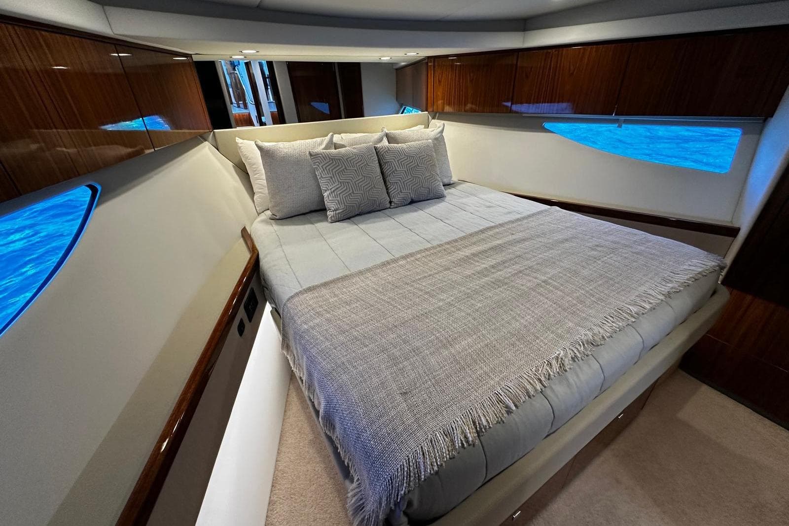 Luxurious bedroom interior of 2023 Riviera 465 SUV yacht with elegant bedding and wood accents.