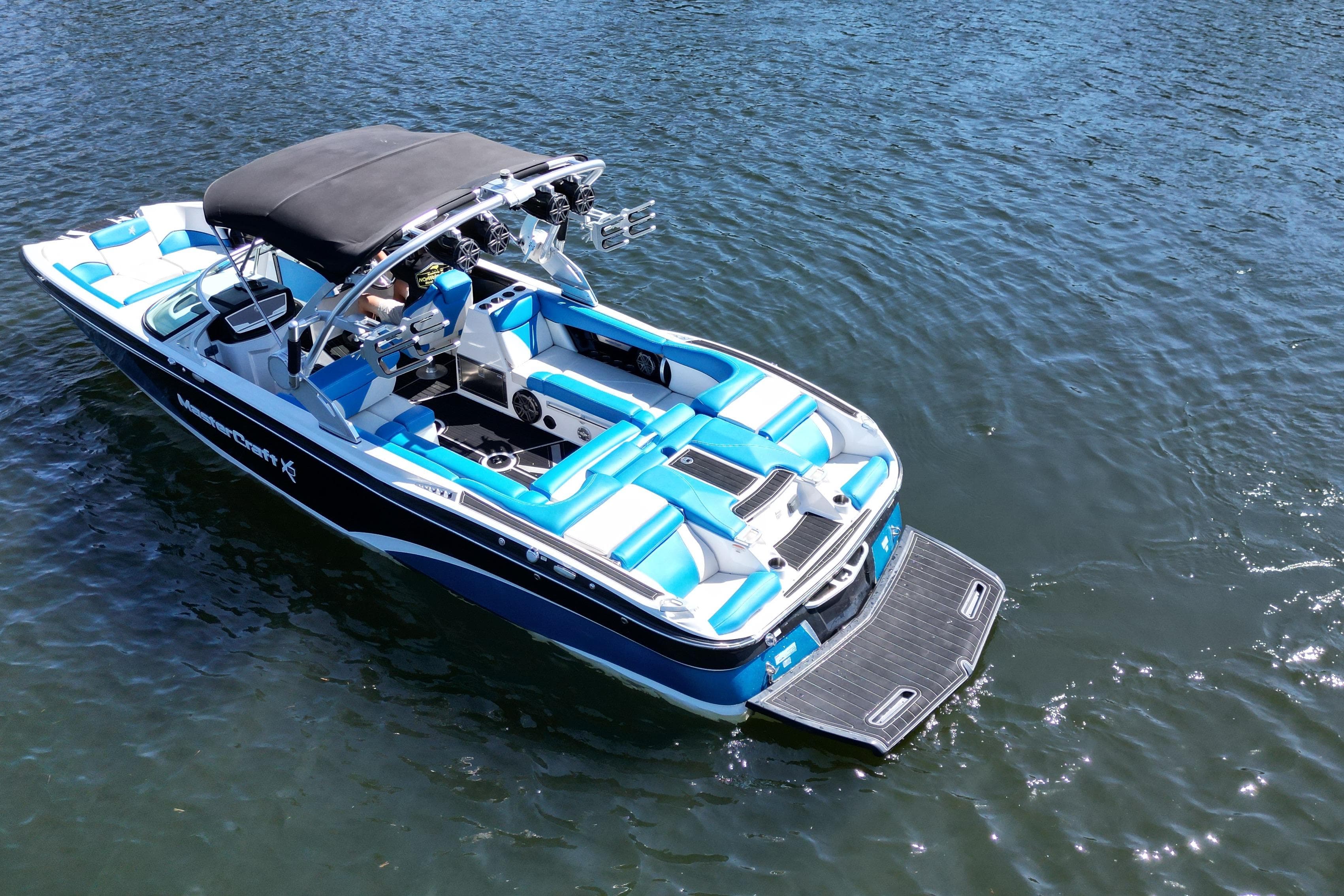 2017 MasterCraft X26 boat with blue and white seating on calm water.