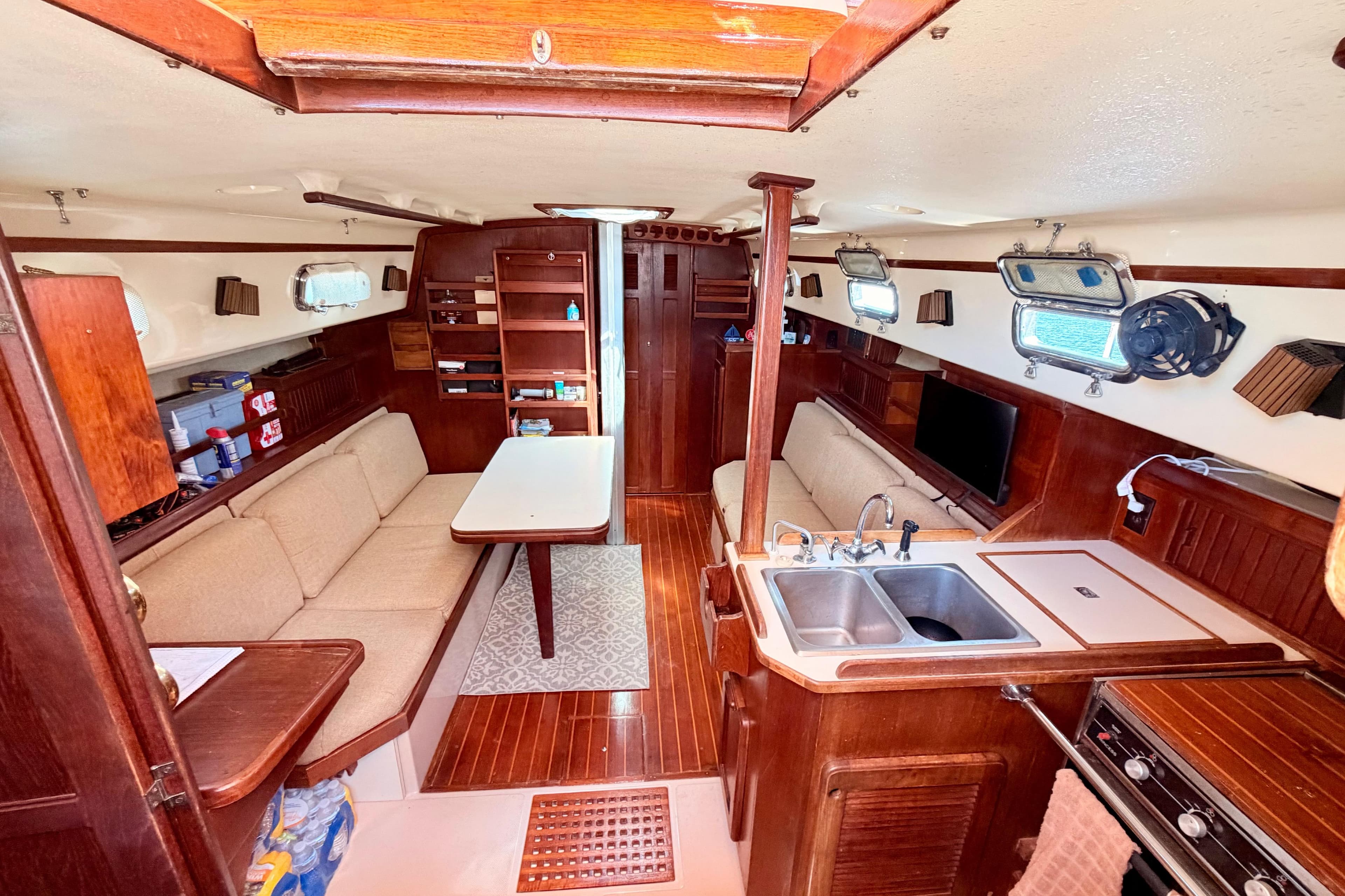 1989 Island Packet Cutter interior with wood finish, cozy seating, and compact kitchen area.