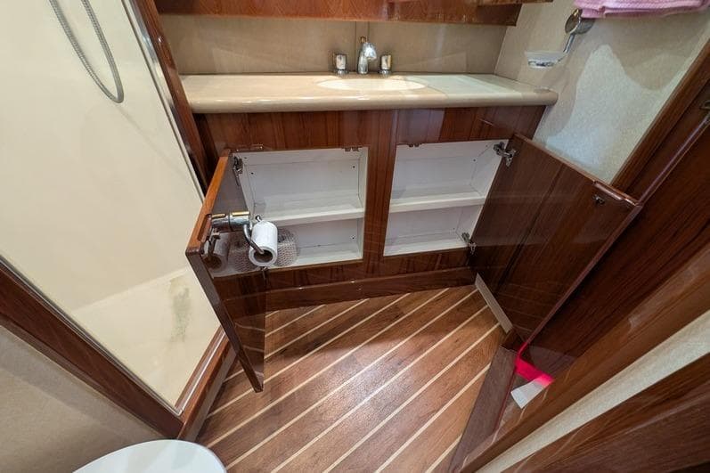 Bathroom interior of 2005 Egg Harbor 43 SportYacht with open wooden cabinets.