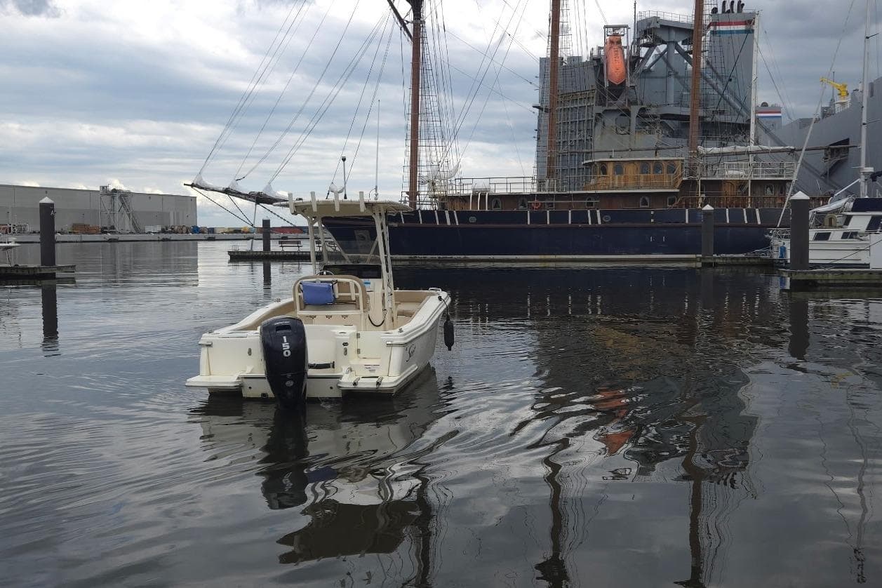 2023 Scout 215 XSF boat docked near a large ship in a marina.