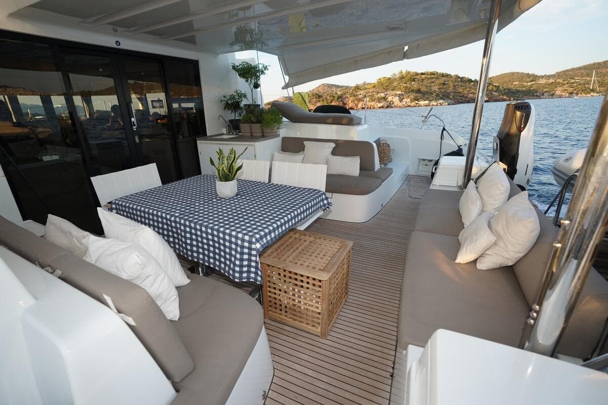 Luxurious Lagoon 50 catamaran deck with seating, table, and scenic ocean view, 2022 model.
