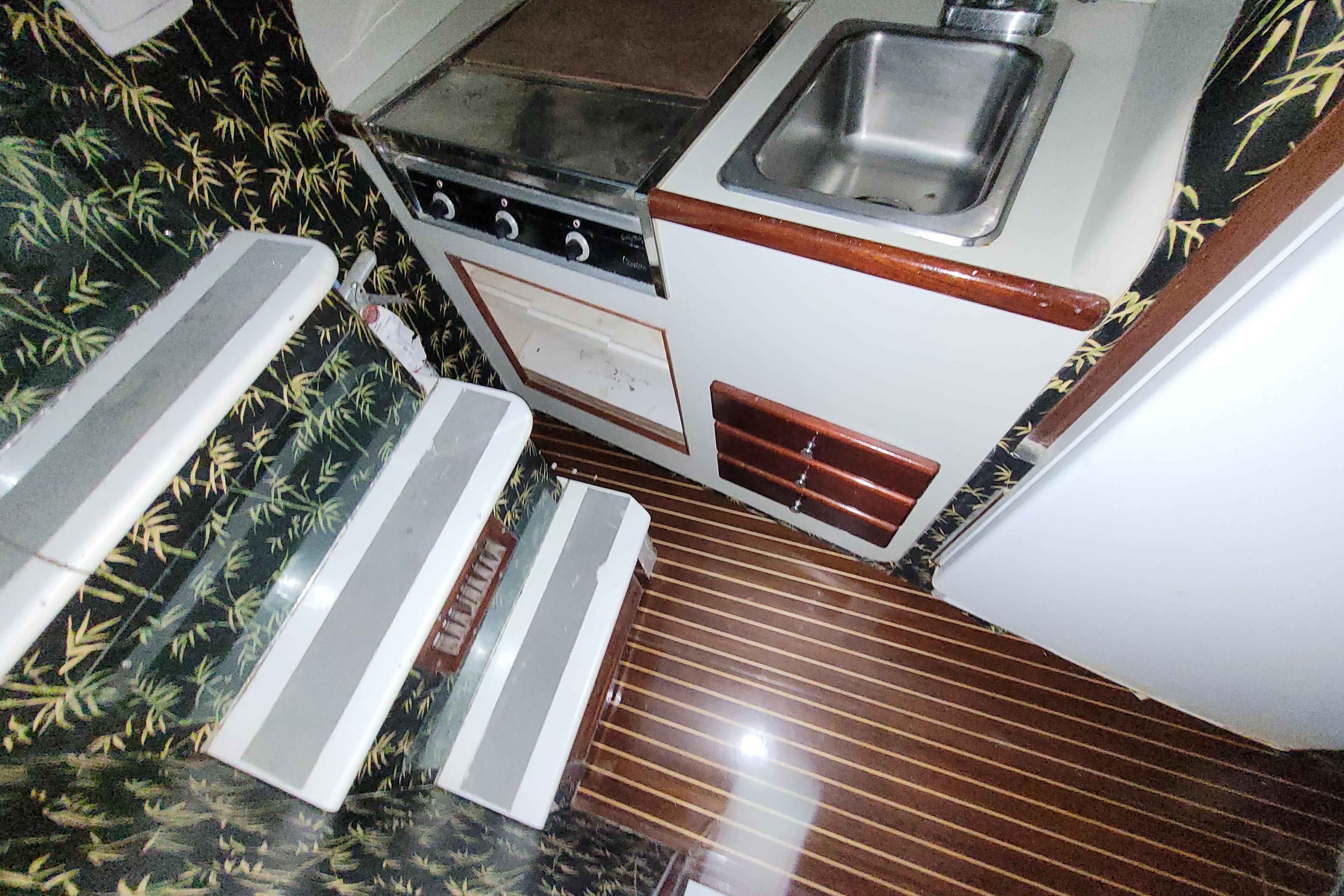 1984 Sunny Briggs 37 Express yacht interior with compact kitchen and patterned walls.