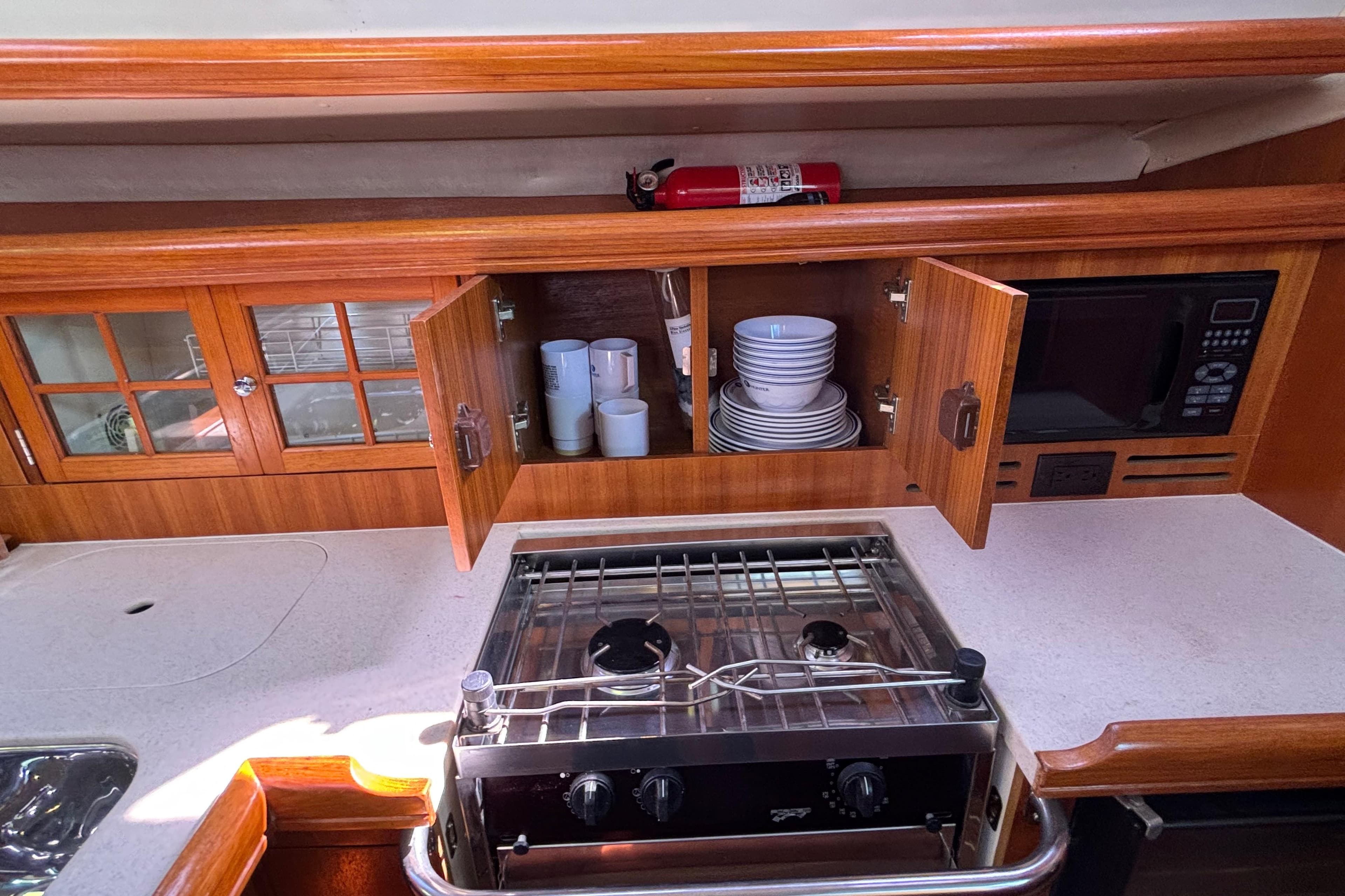 Compact kitchen in a 2006 Hunter 38 yacht with stove, microwave, and wooden cabinets.