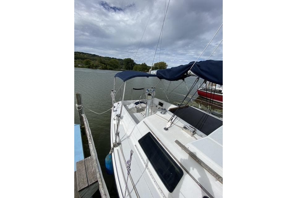 1990 Hunter 27 sailboat docked on a calm lake under cloudy skies.