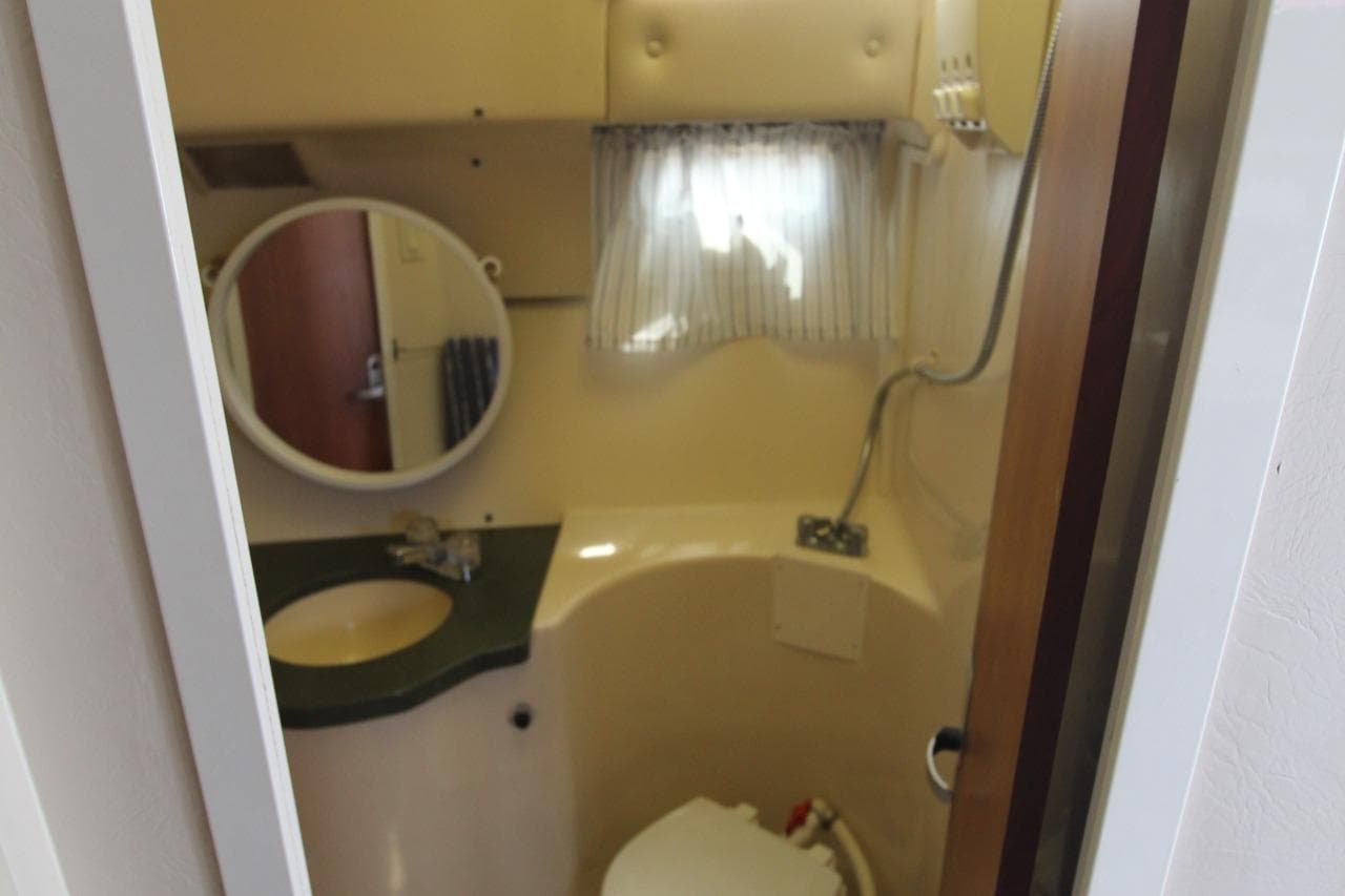 1999 Mainship 31 Sedan Bridge bathroom with sink, mirror, and toilet.