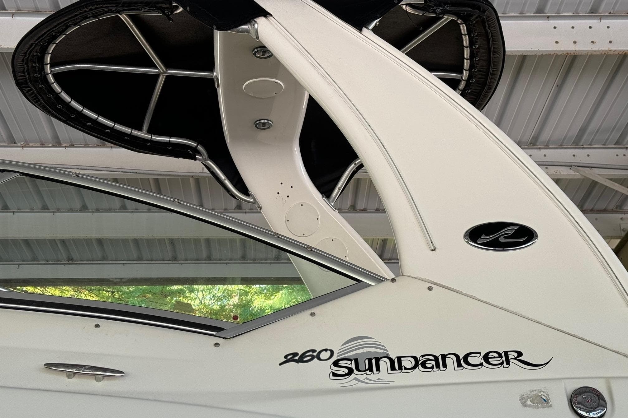 2007 Sea Ray 260 Sundancer boat under a metal roof, showcasing sleek design and logo.
