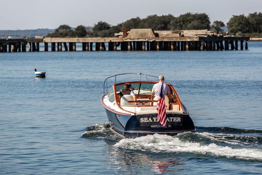 Hinckley T29R boat from 2003 cruising on calm waters near a pier.