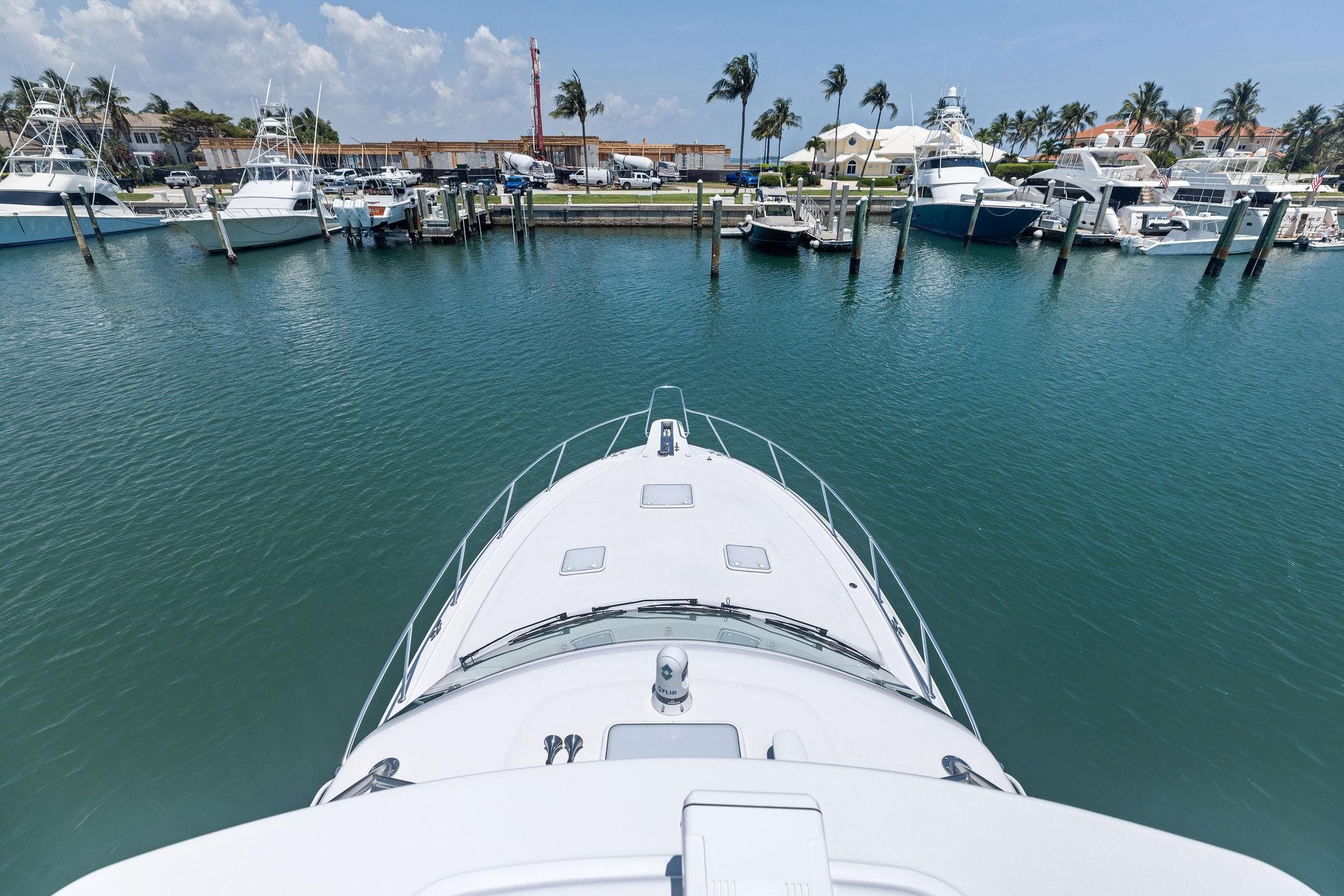 Bow view of 2016 Hatteras Express Sportfish in a marina with palm trees.