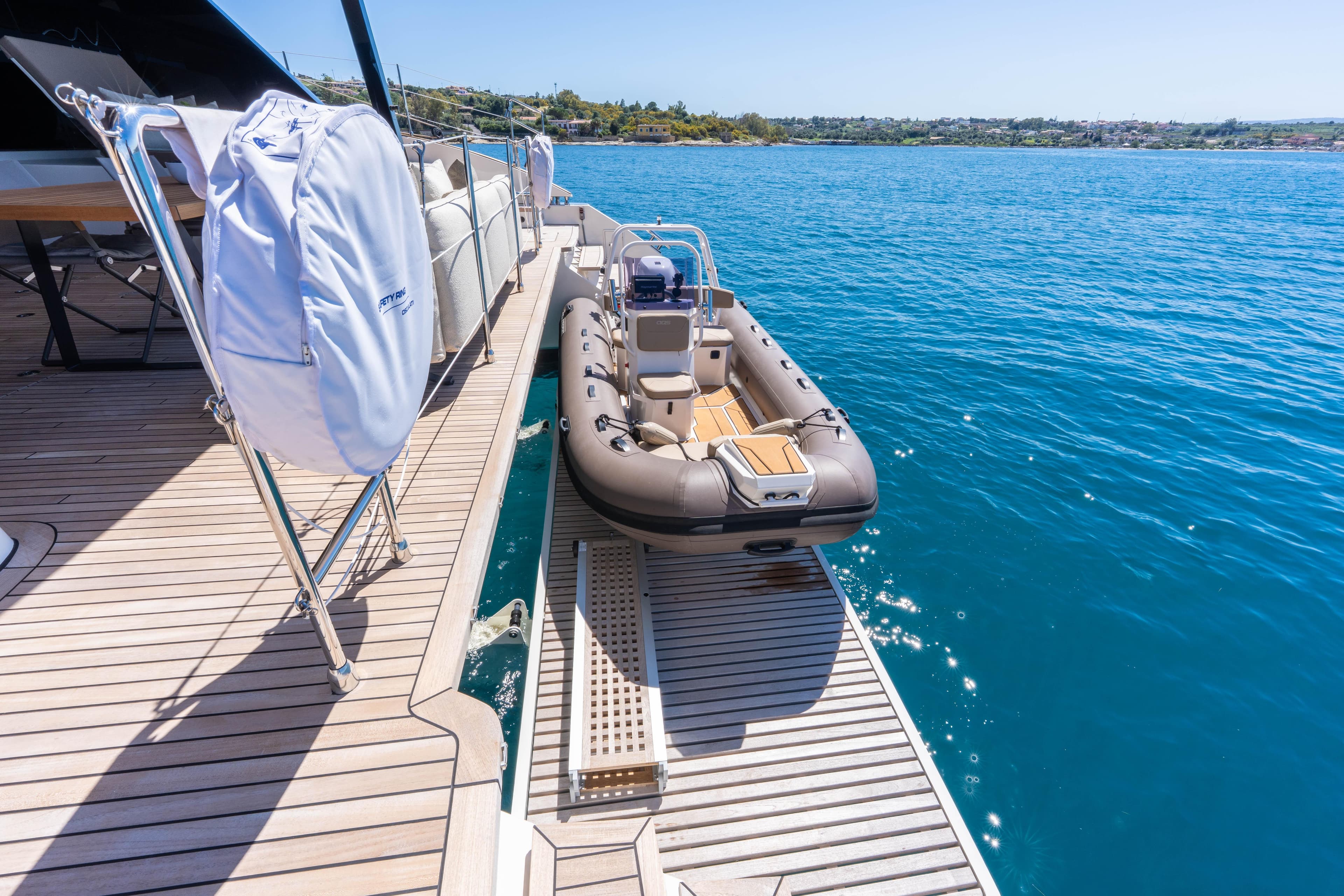 Luxury Sunreef 60 yacht deck with tender boat, 2025 model, on serene blue water.