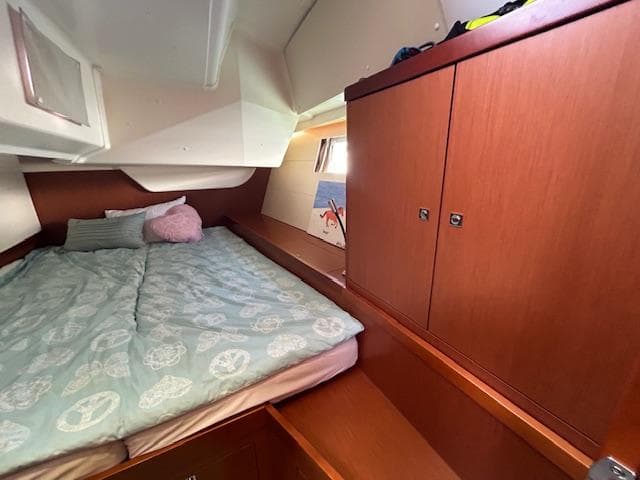 Cozy bedroom in 2013 Beneteau 48 sailboat with wooden cabinets and a double bed.