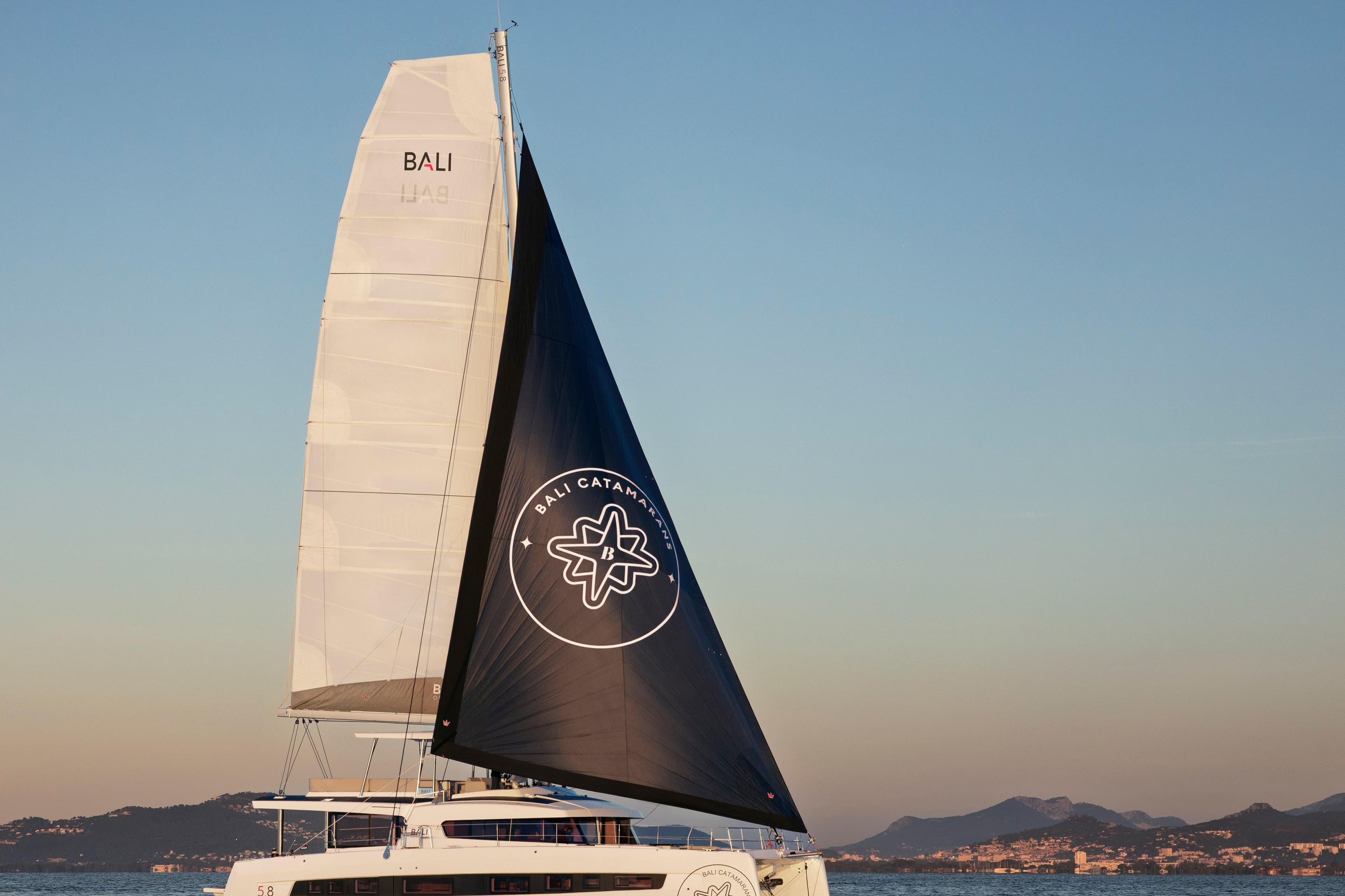 Sailing catamaran Bali 5.8, 2026 model, with scenic coastal backdrop.