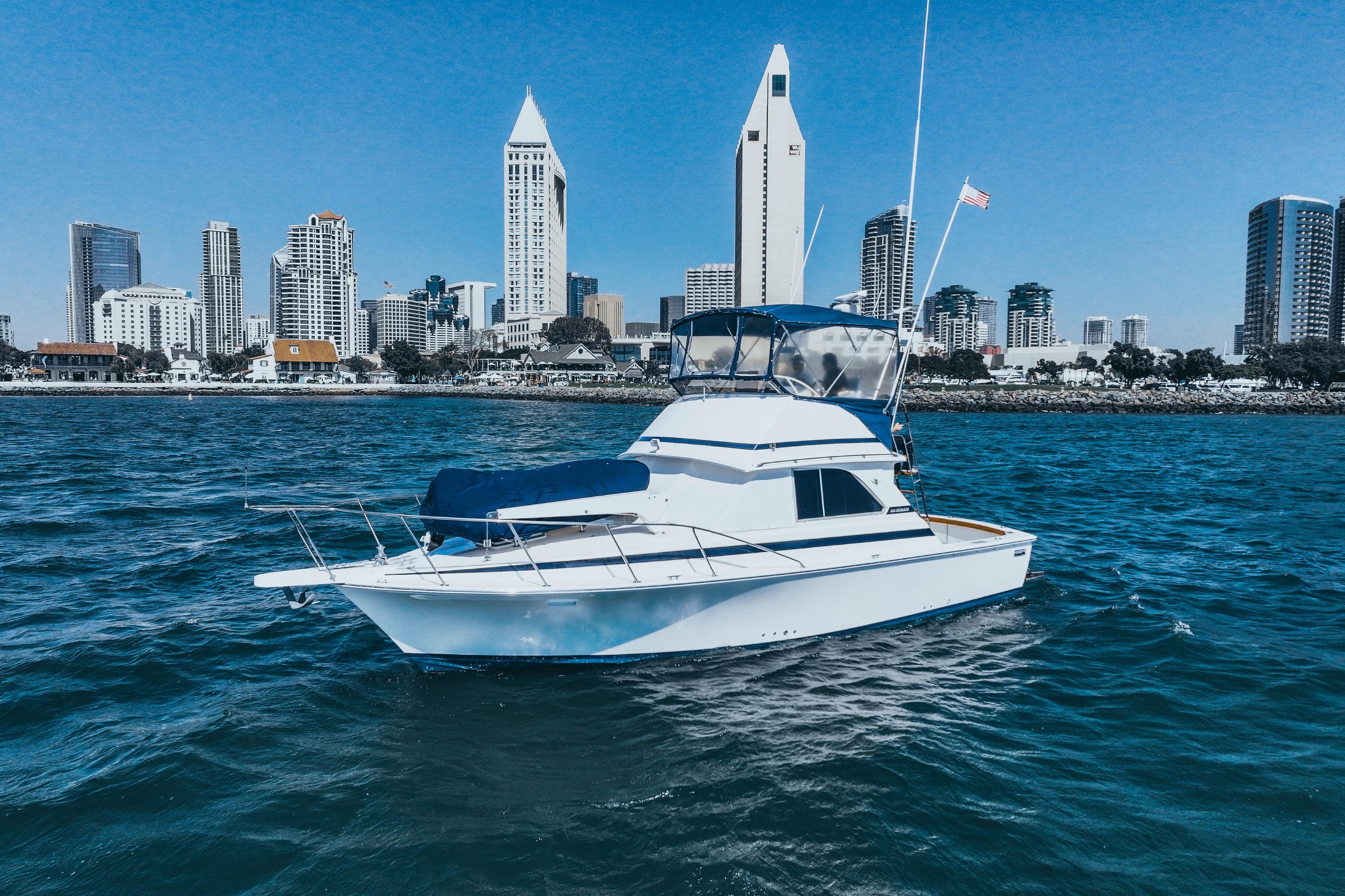 1984 Bertram 35 Convertible yacht on water with city skyline backdrop.