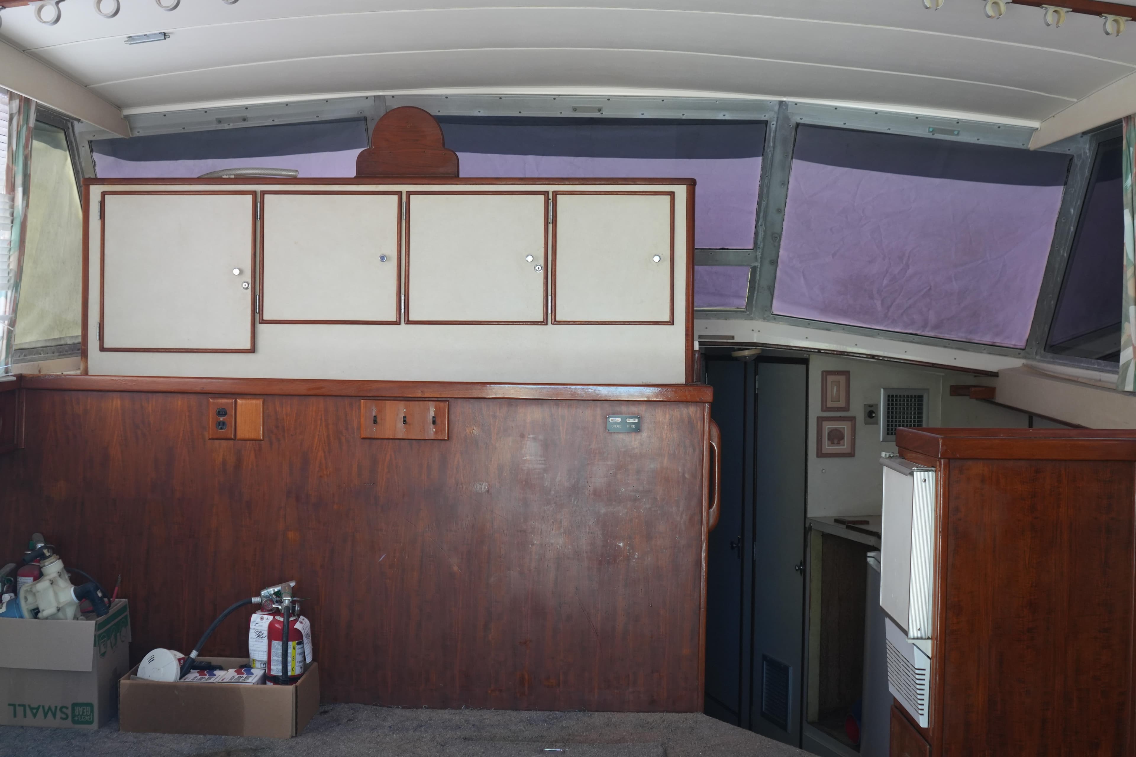 Interior of a 1977 Bertram 46.6 yacht with wooden cabinetry and large windows.