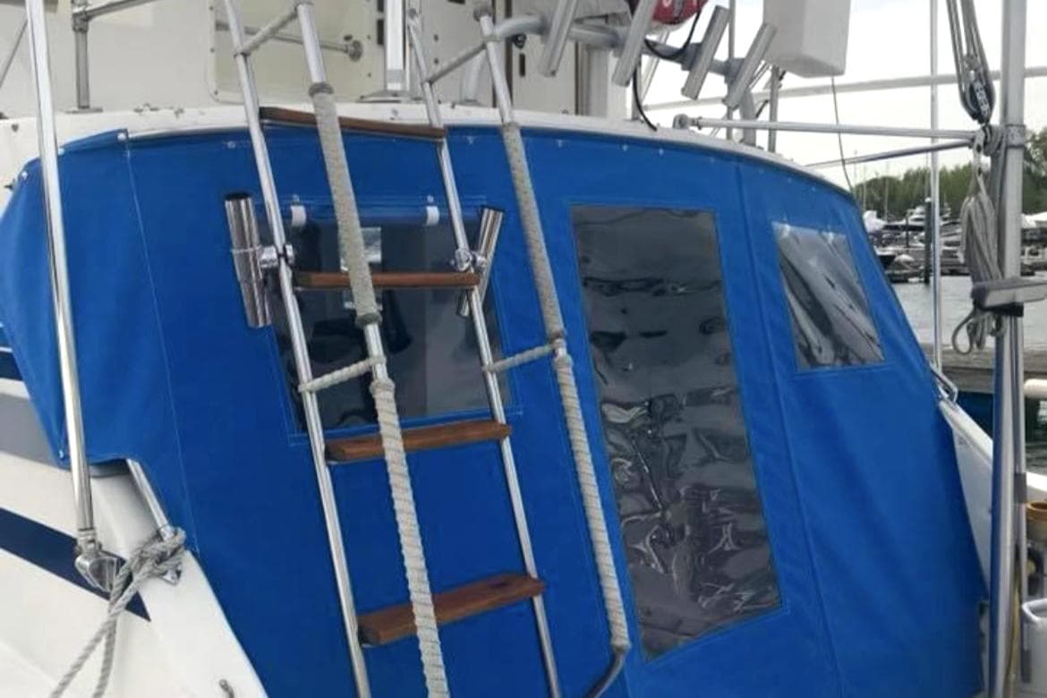 1980 Bertram 33 Sport Fisherman with blue canvas cover and ladder.