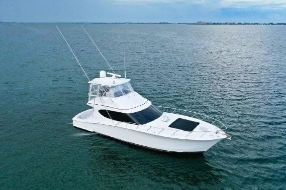 2013 Hatteras GT54 yacht cruising on open water under a cloudy sky.
