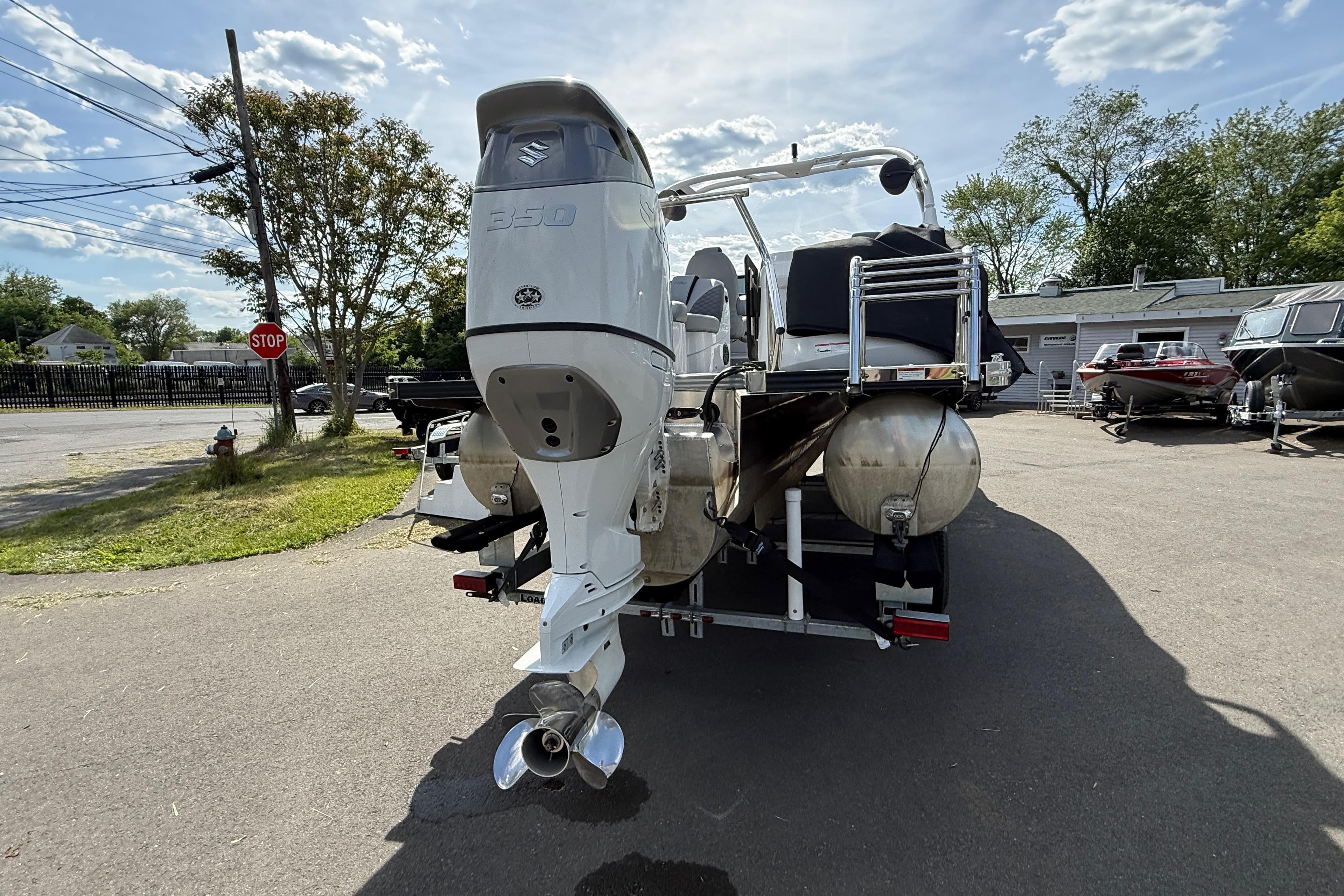 2023 Manitou 25 LX RFXW pontoon boat with powerful outboard motor, parked outdoors.