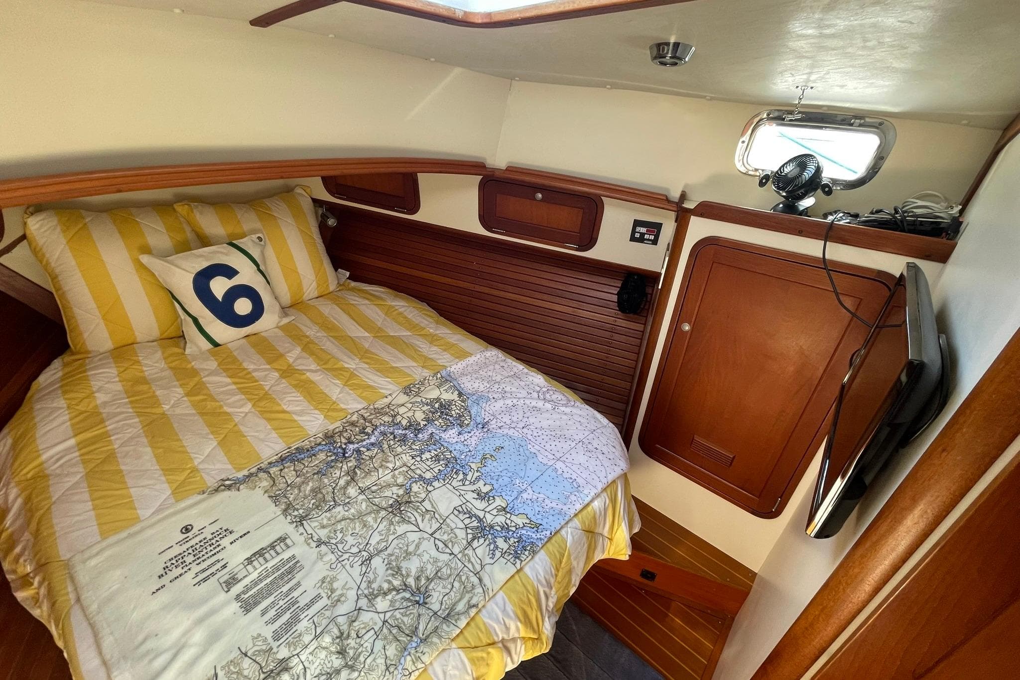 Cozy cabin interior of 1999 Legacy Yachts 40 Sedan with nautical bedding and wood paneling.