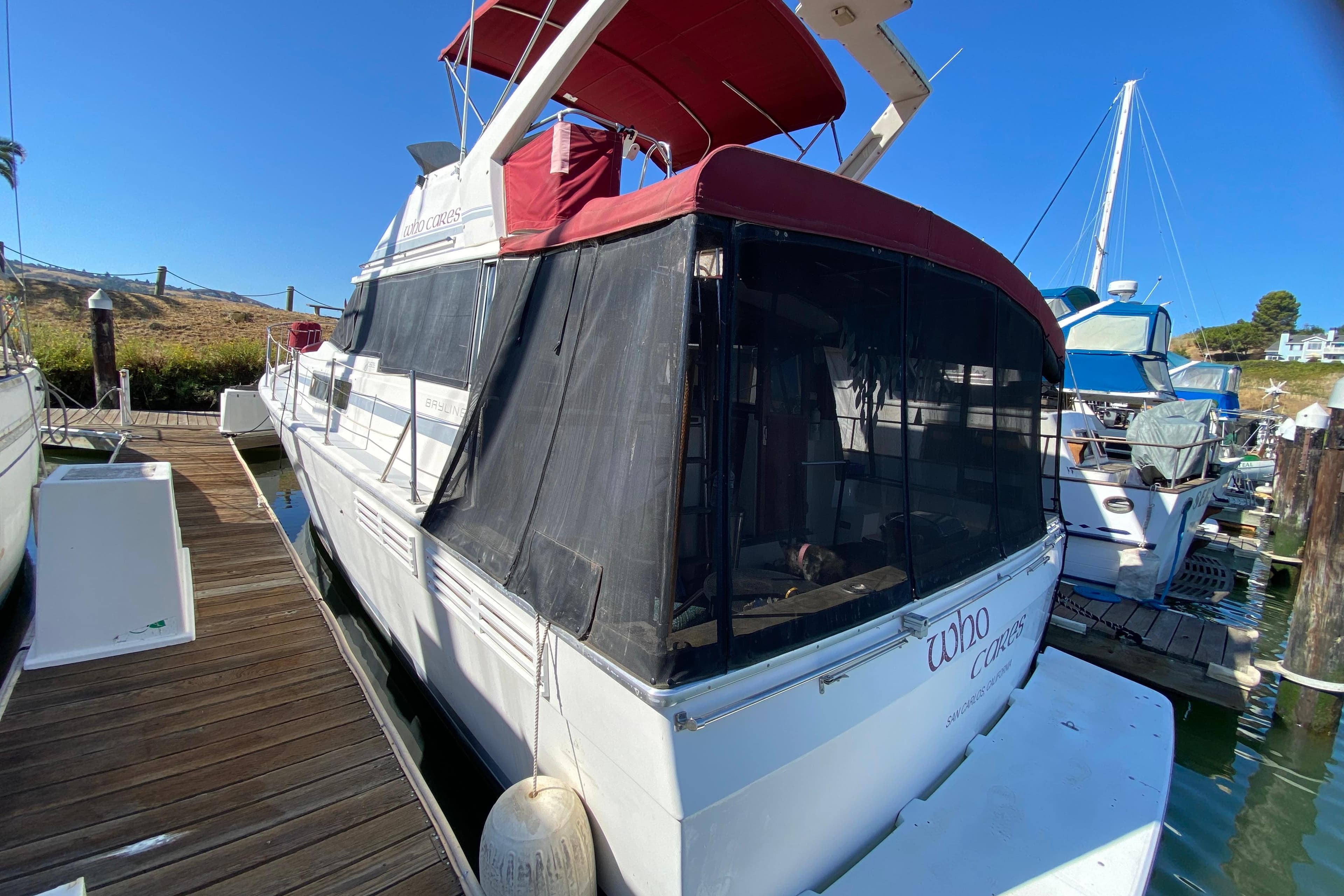 1989 Bayliner 3888 Motoryacht docked, featuring red canopy and black mesh enclosure.