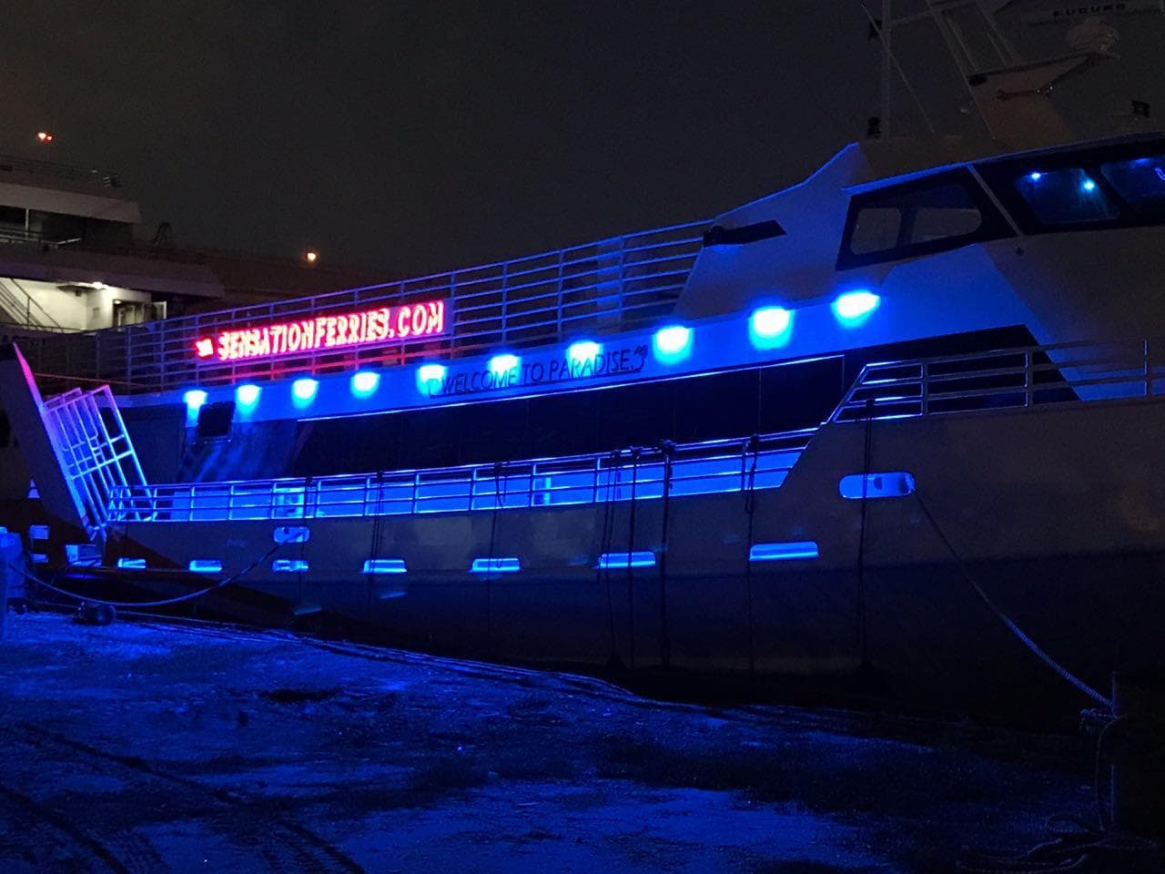 High-speed passenger ferry with blue lights, Midship Marine, 1981 model, docked at night.
