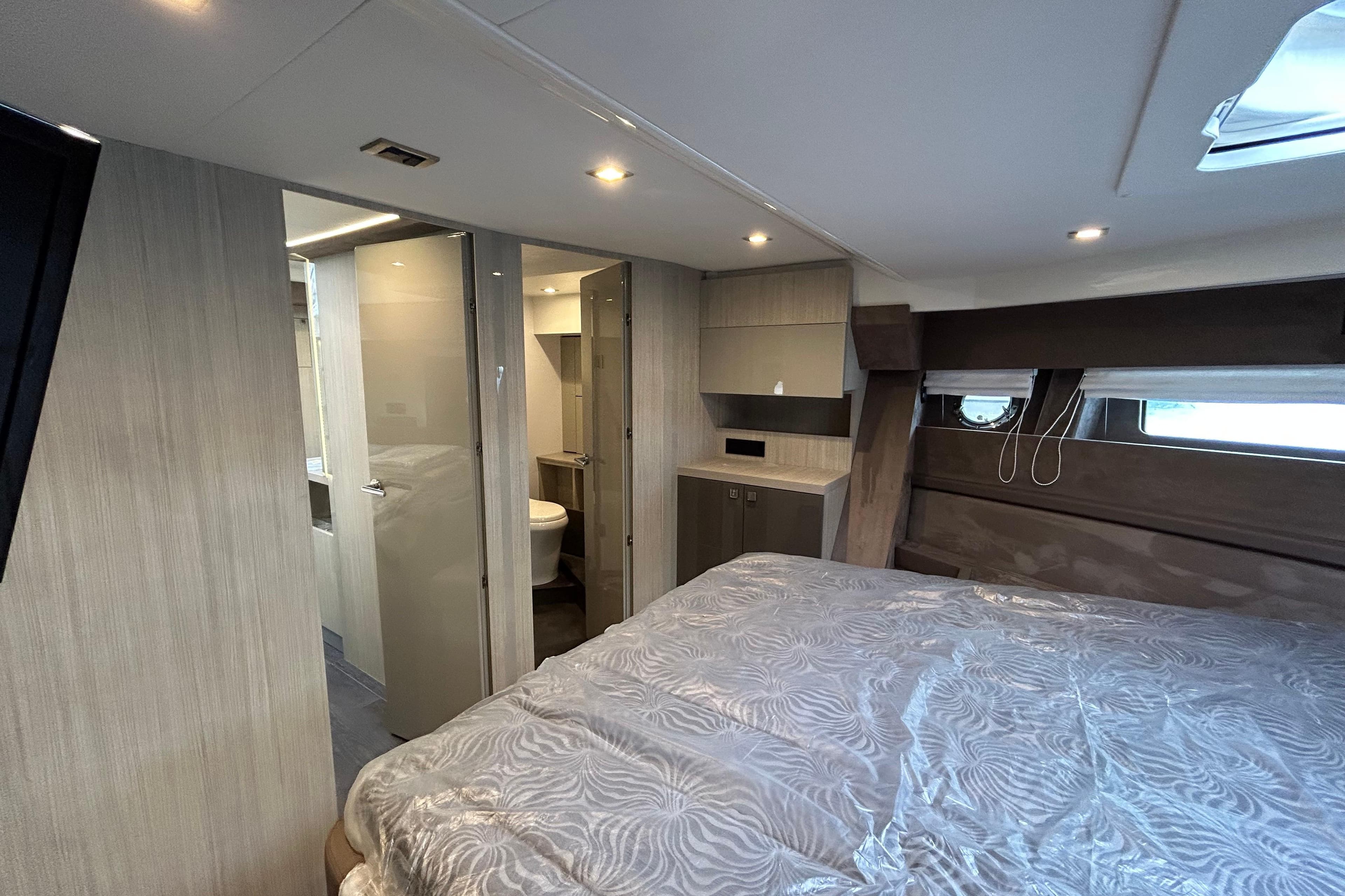 Luxurious interior of 2023 Cranchi 60 ST yacht with modern bedroom and ensuite bathroom.