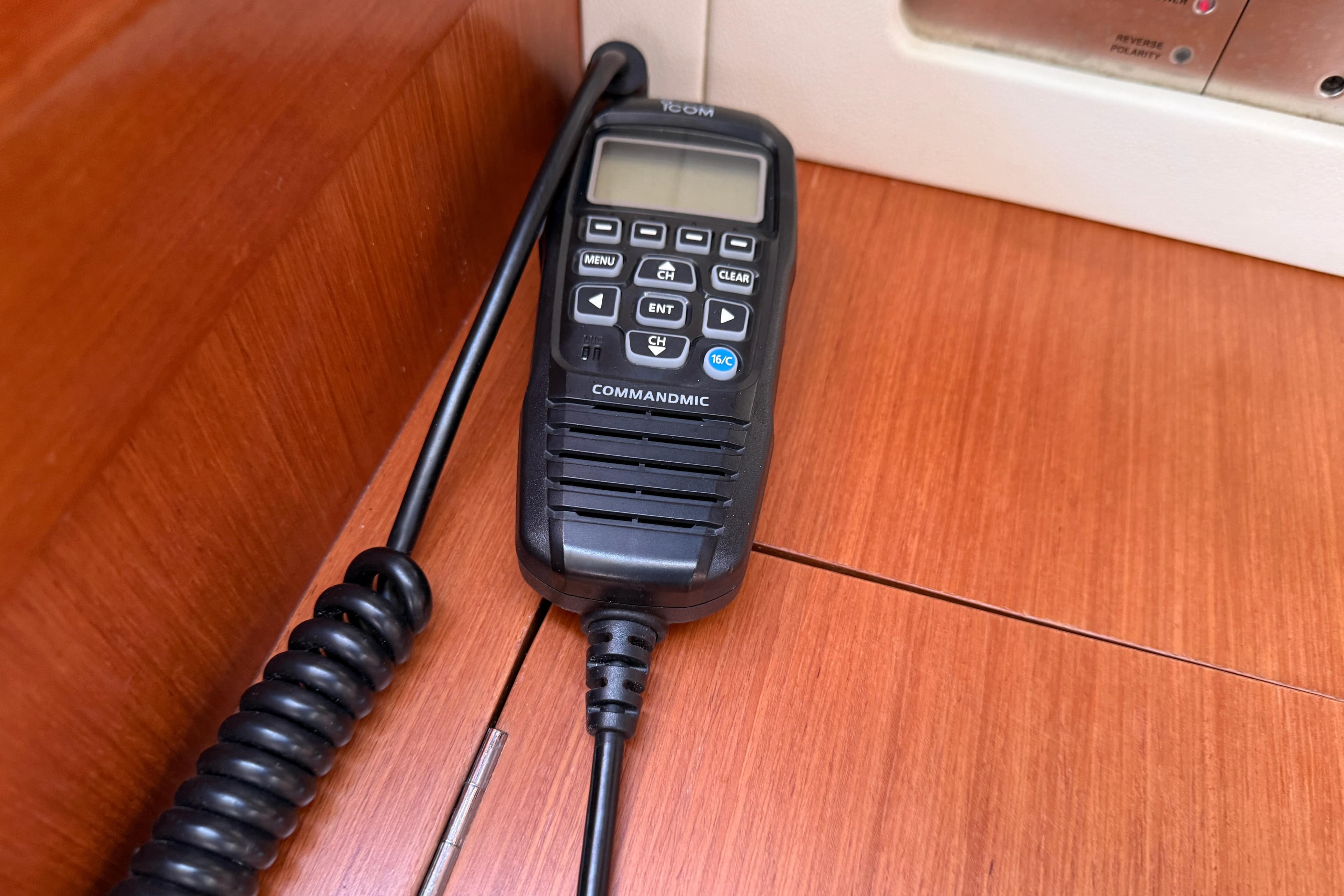 VHF radio handset on Beneteau Oceanis 43 yacht, 2010 model, resting on wooden surface.
