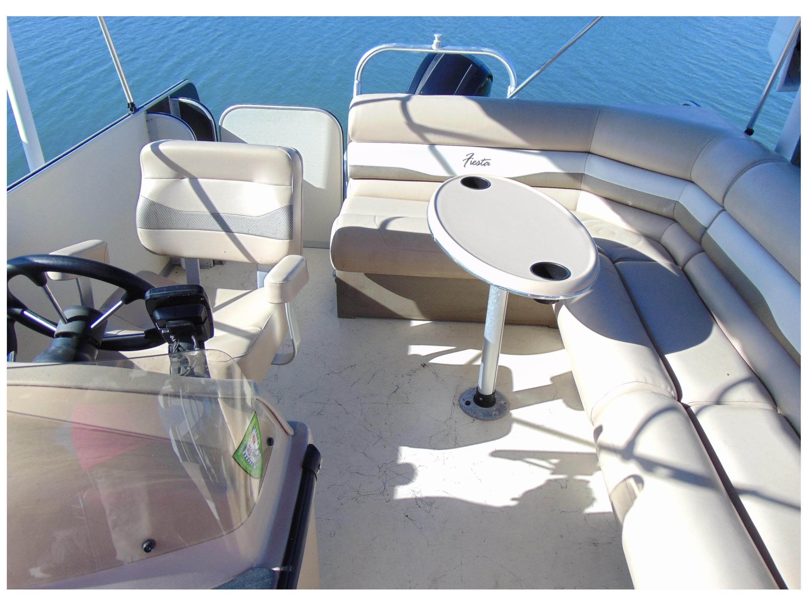 2017 Fiesta 22 Beachcomber boat interior with seating and table on calm water.