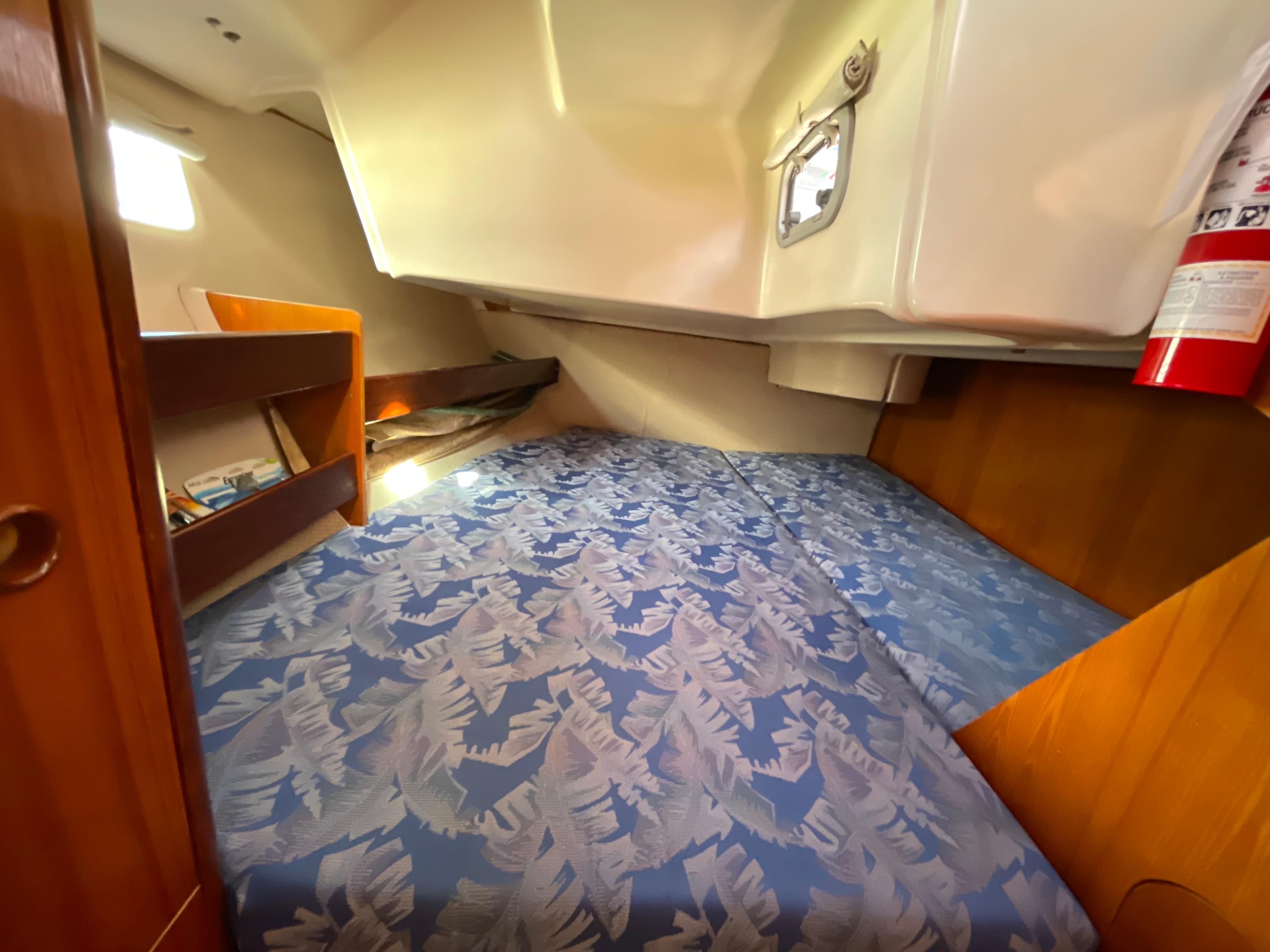 Cozy cabin interior of 1994 Beneteau 352 sailboat with patterned bedding and wooden accents.