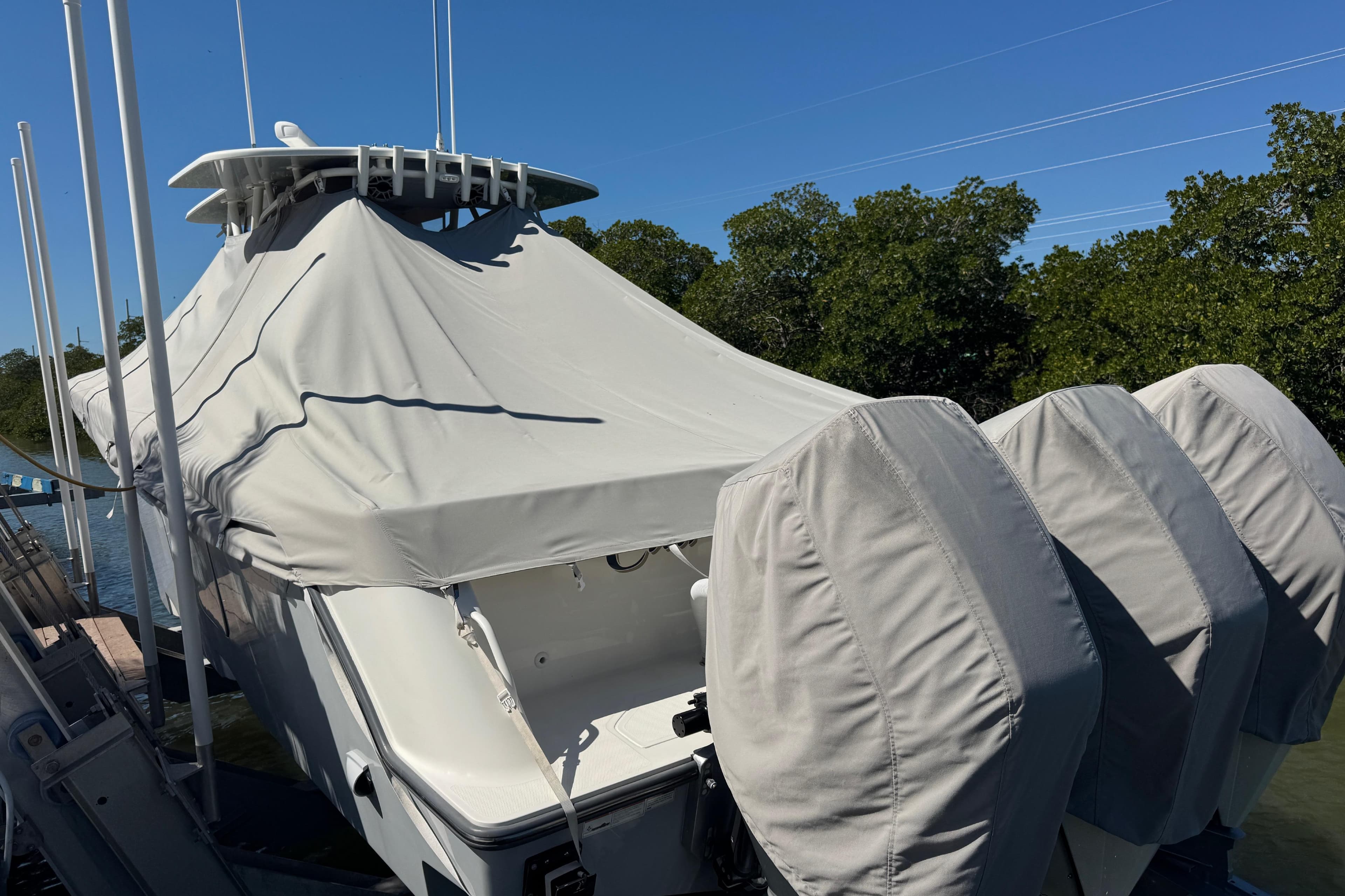 2021 SeaVee Boats 370Z covered, docked with triple outboard engines, surrounded by trees.