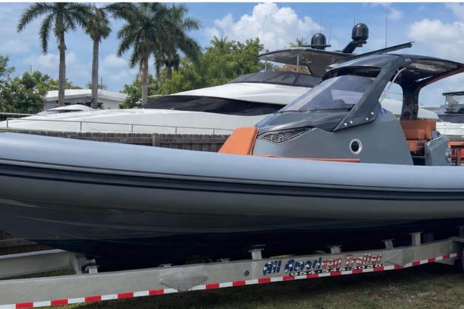 2019 SACS Strider 13 OB boat on trailer, with palm trees and yachts in the background.