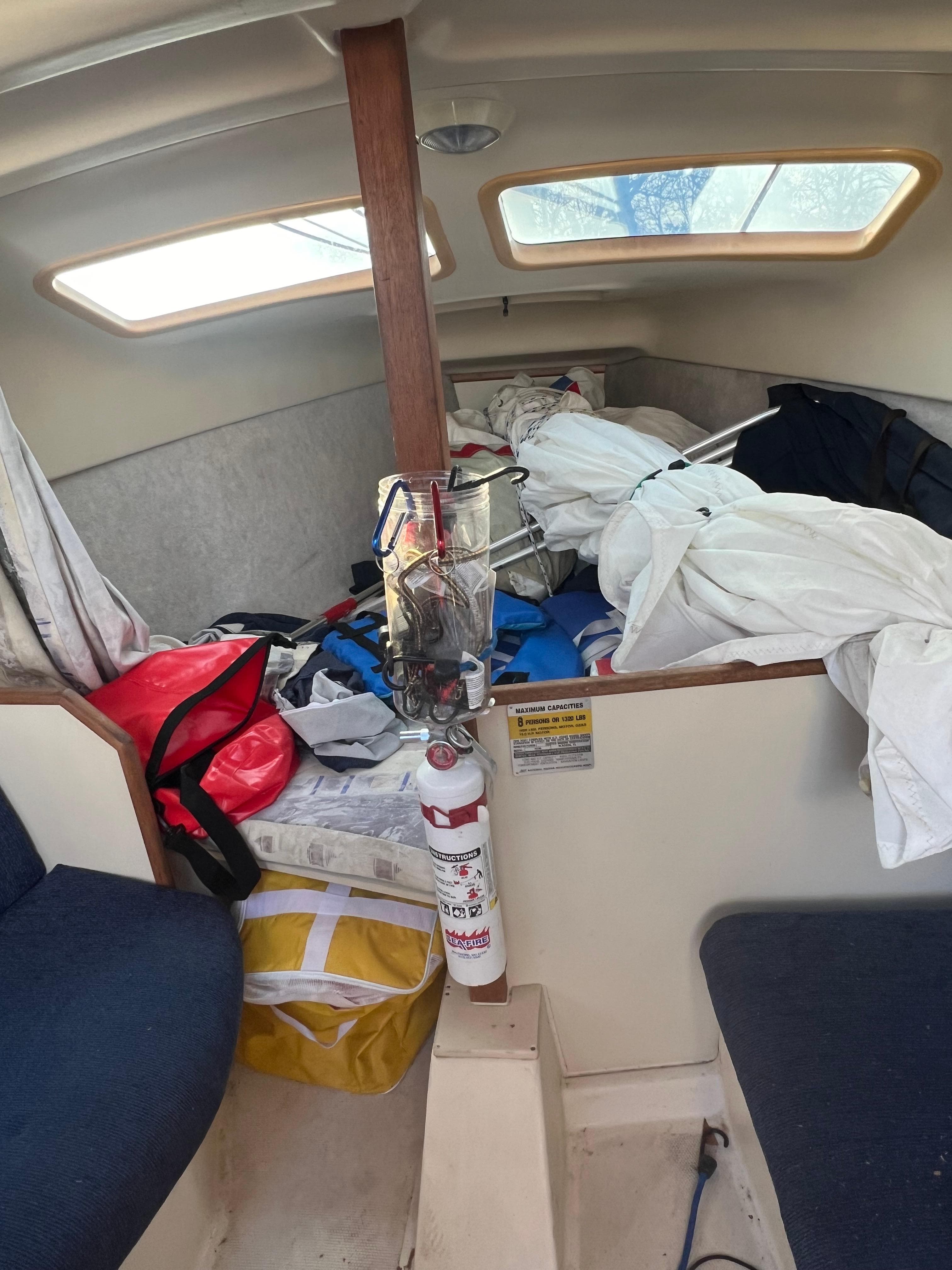 Interior of a 2002 Hunter 240 sailboat with cluttered cabin and fire extinguisher.