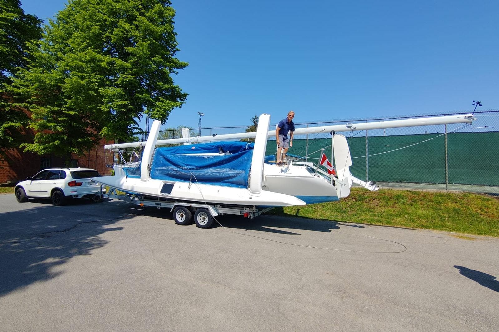 A 2000 Farrier 31 sailboat on a trailer, parked beside a white SUV.