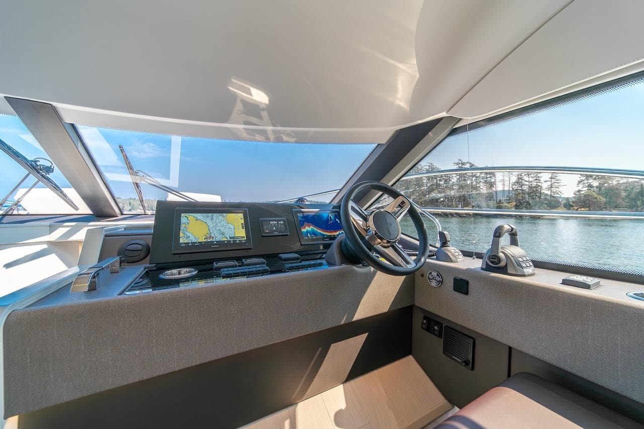 Cockpit of 2025 Prestige F4.9 yacht with modern navigation equipment and scenic water view.