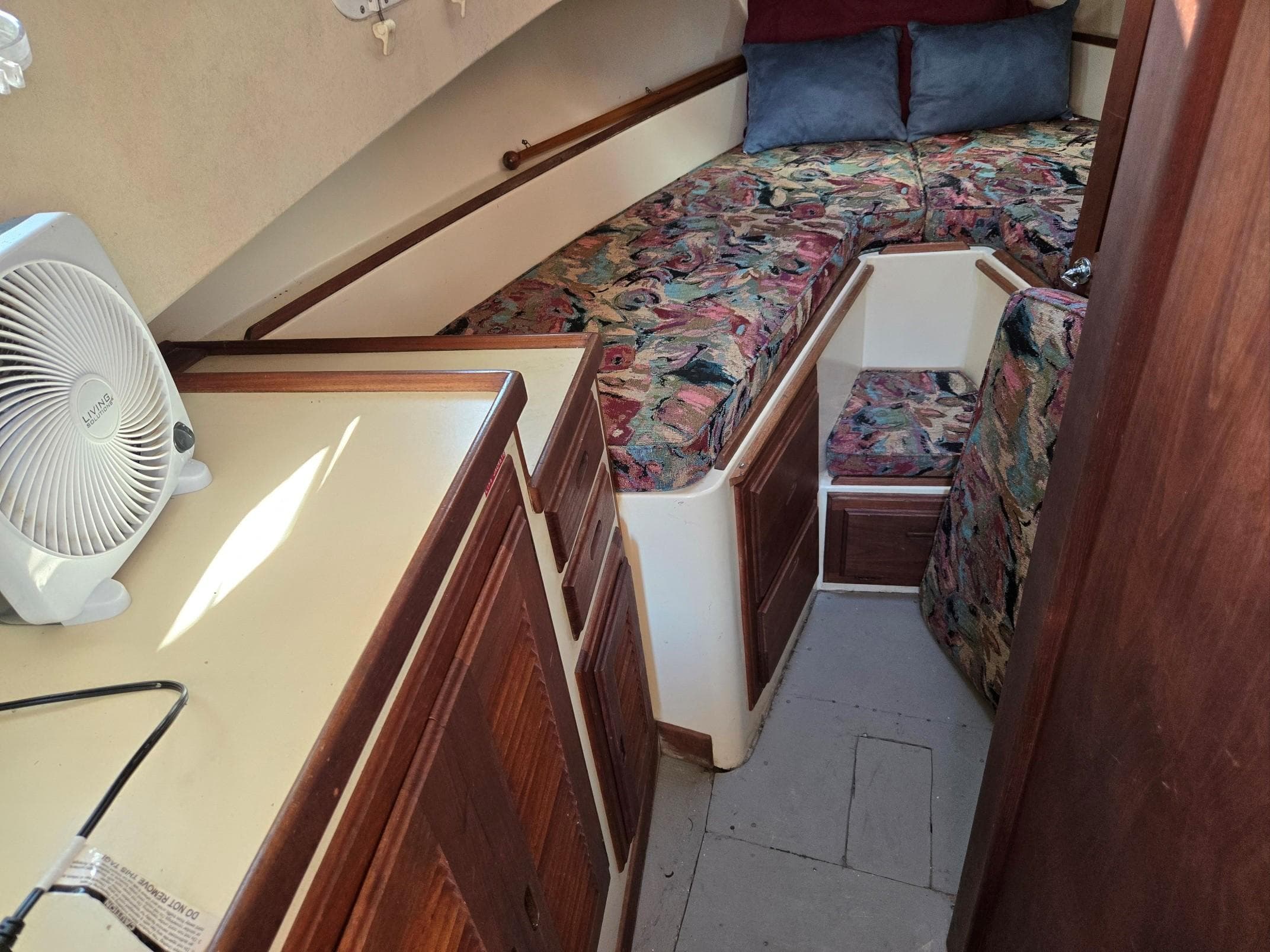 1974 Willard Nomad interior with patterned cushions, wooden cabinets, and a small fan.