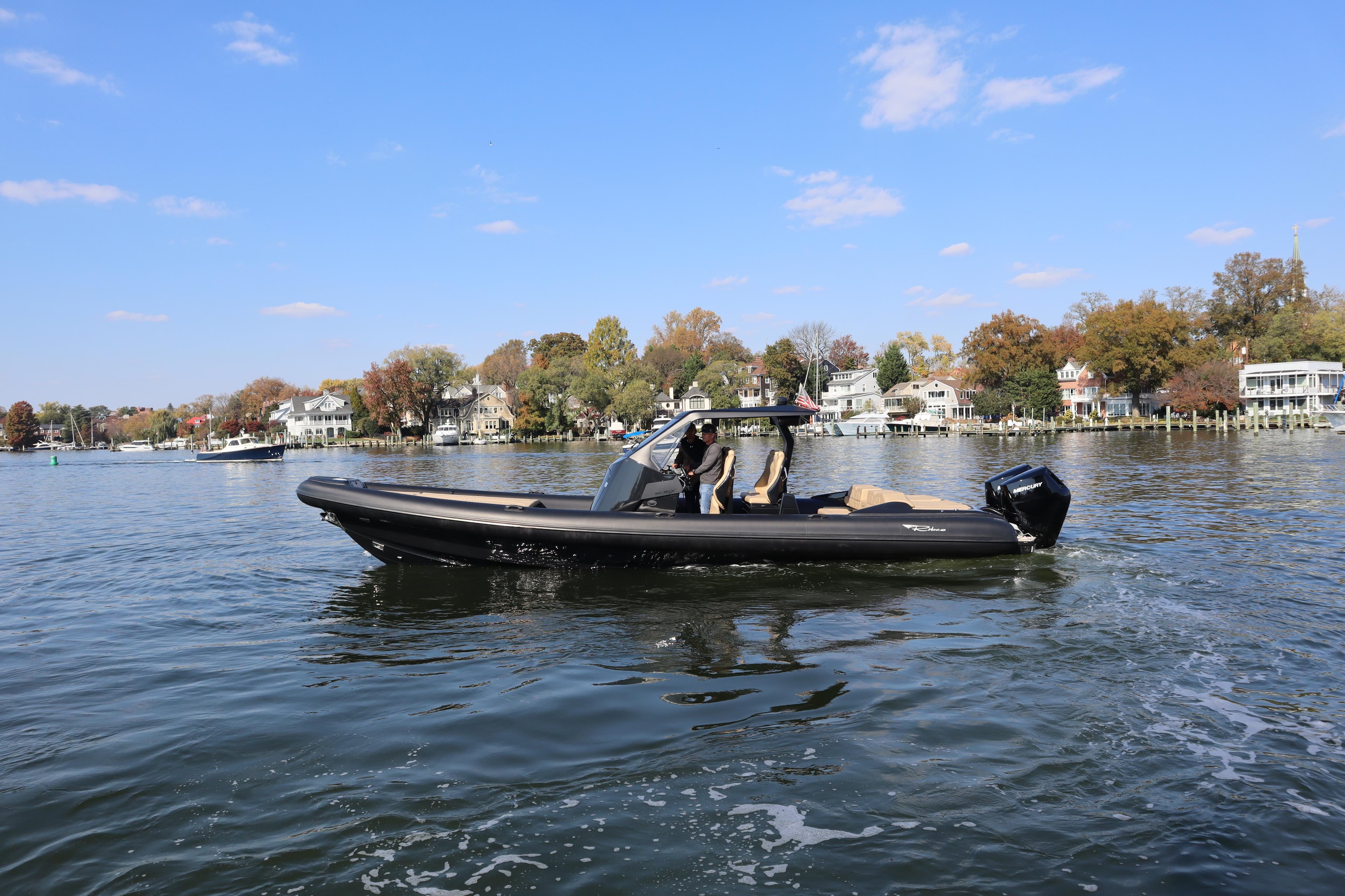 2023 Ribco Seafarer 36 X boat cruising on a scenic lake with autumn foliage.