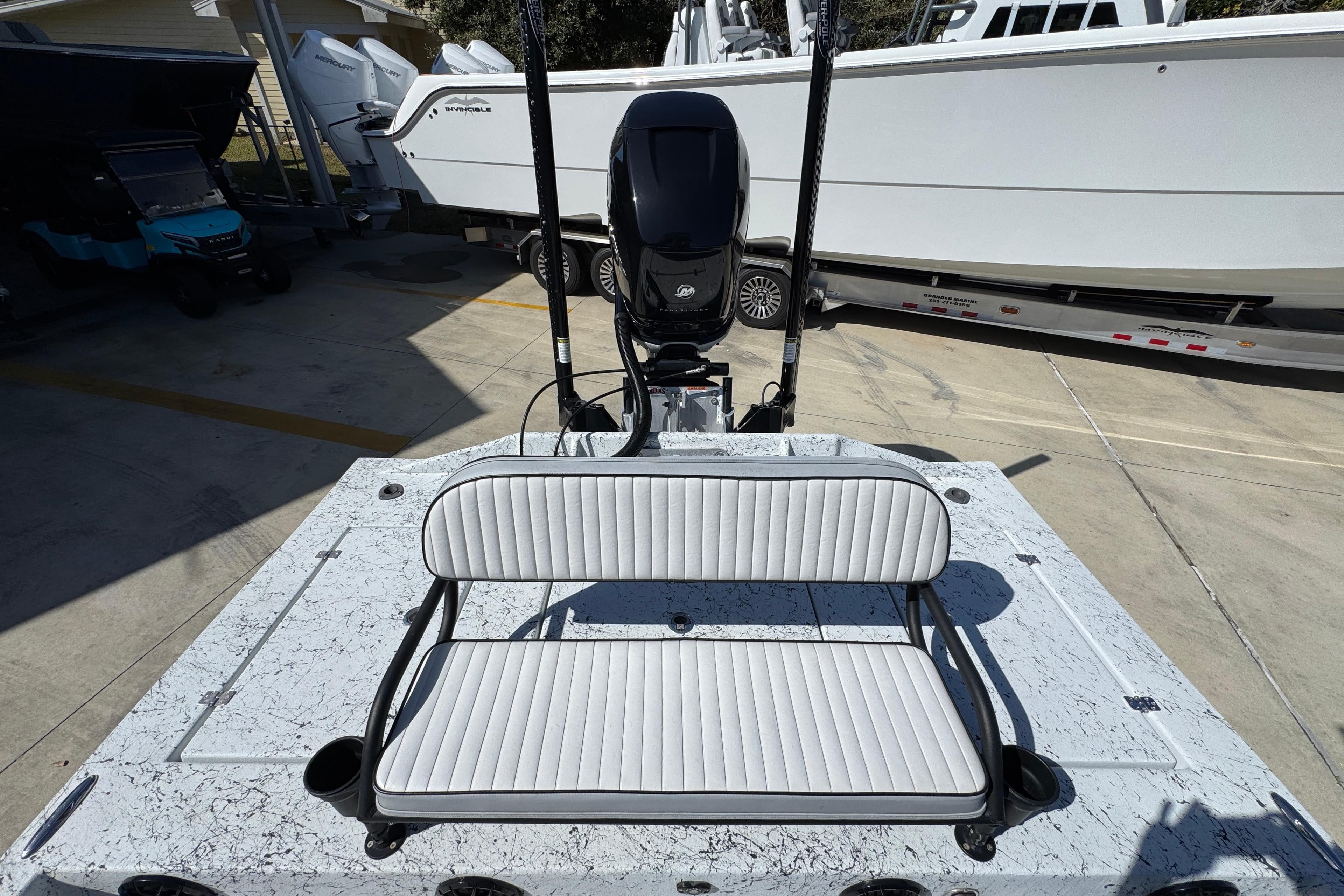 2023 Dek Kat 27 Trilogy boat with white seating and motor, parked in a marina.