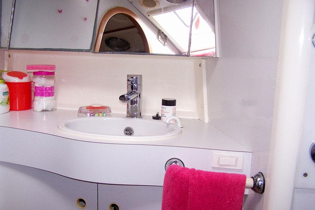 Bathroom sink area on a 1990 Wauquiez Centurion 47 yacht, featuring modern fixtures and storage.