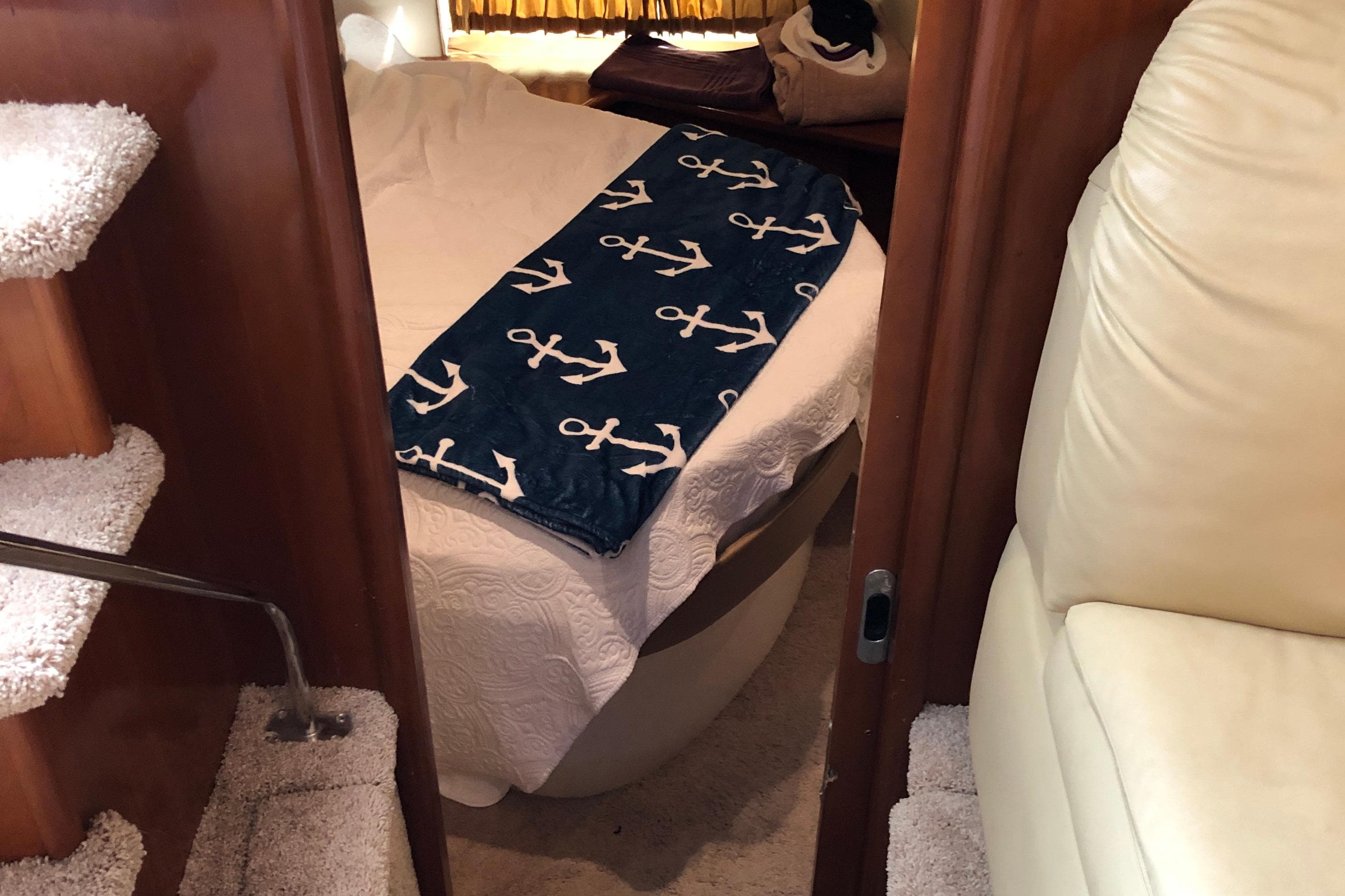 Interior of 2004 Carver 366 Motor Yacht with cozy bed and nautical-themed blanket.