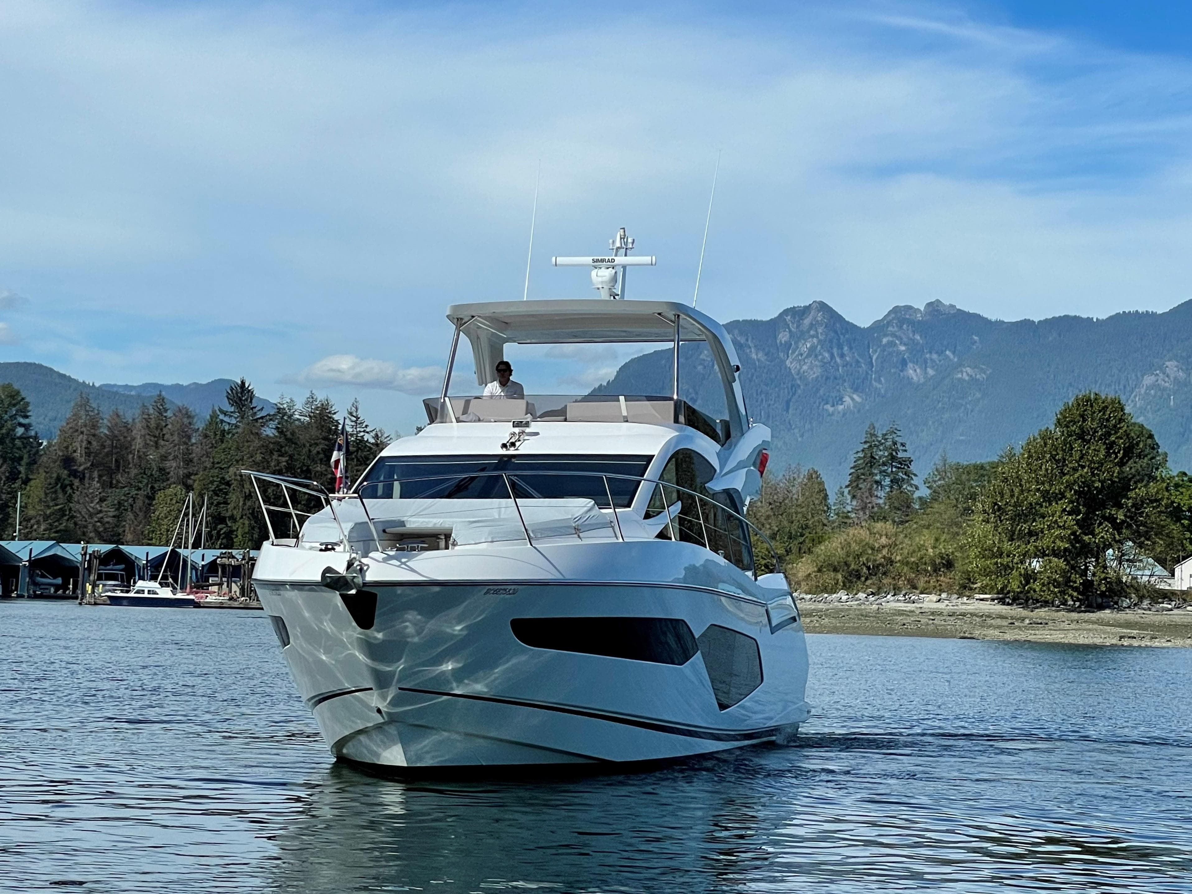 Sunseeker Manhattan 52 yacht cruising on a serene lake with mountain backdrop, 2020 model.