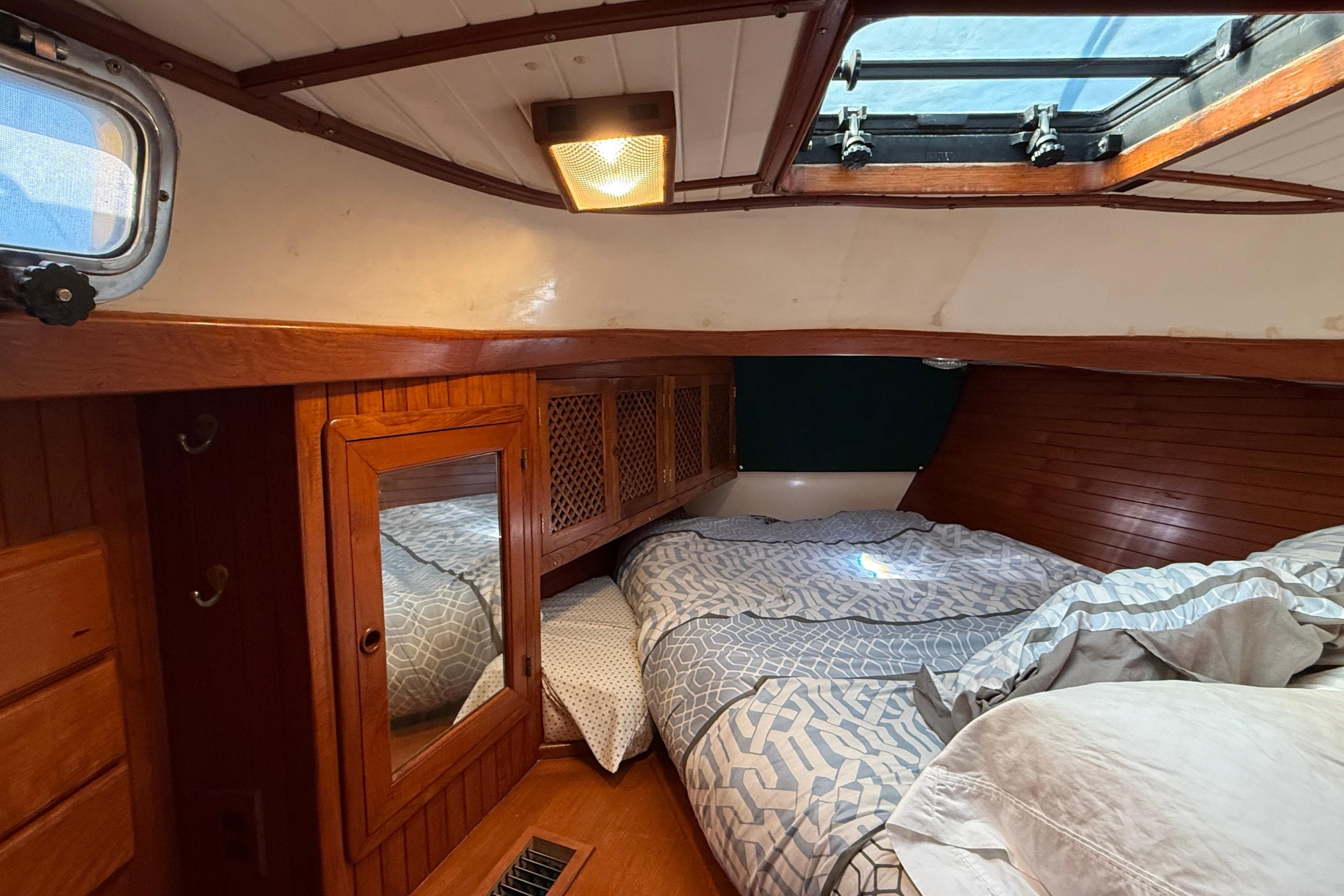 Cozy cabin interior of 1986 Westwind 38 sailboat with wooden accents and bedding.