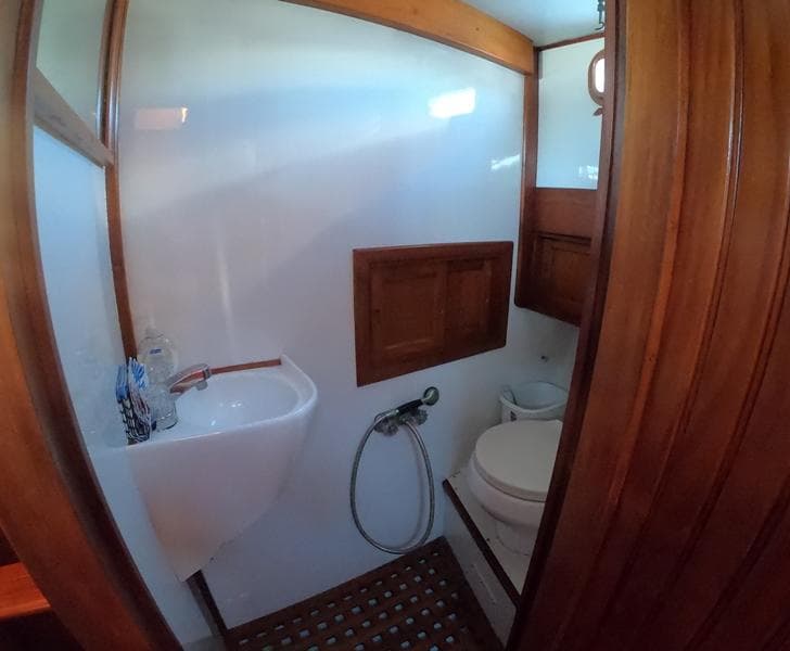 1977 CHB 34 boat bathroom with sink, toilet, and wooden accents.