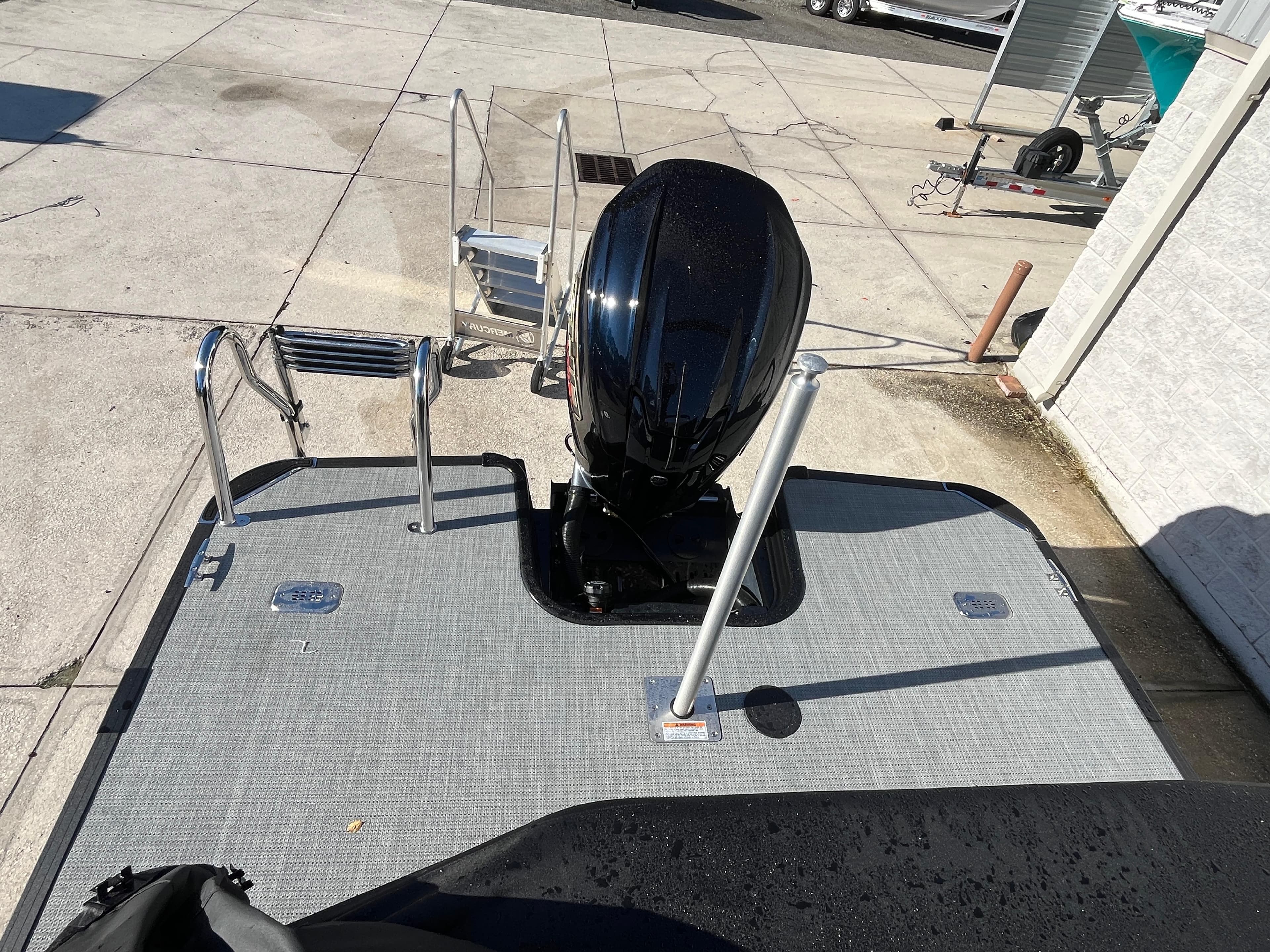 2025 Starcraft EXS-3 boat with outboard motor and swim platform, parked on concrete.