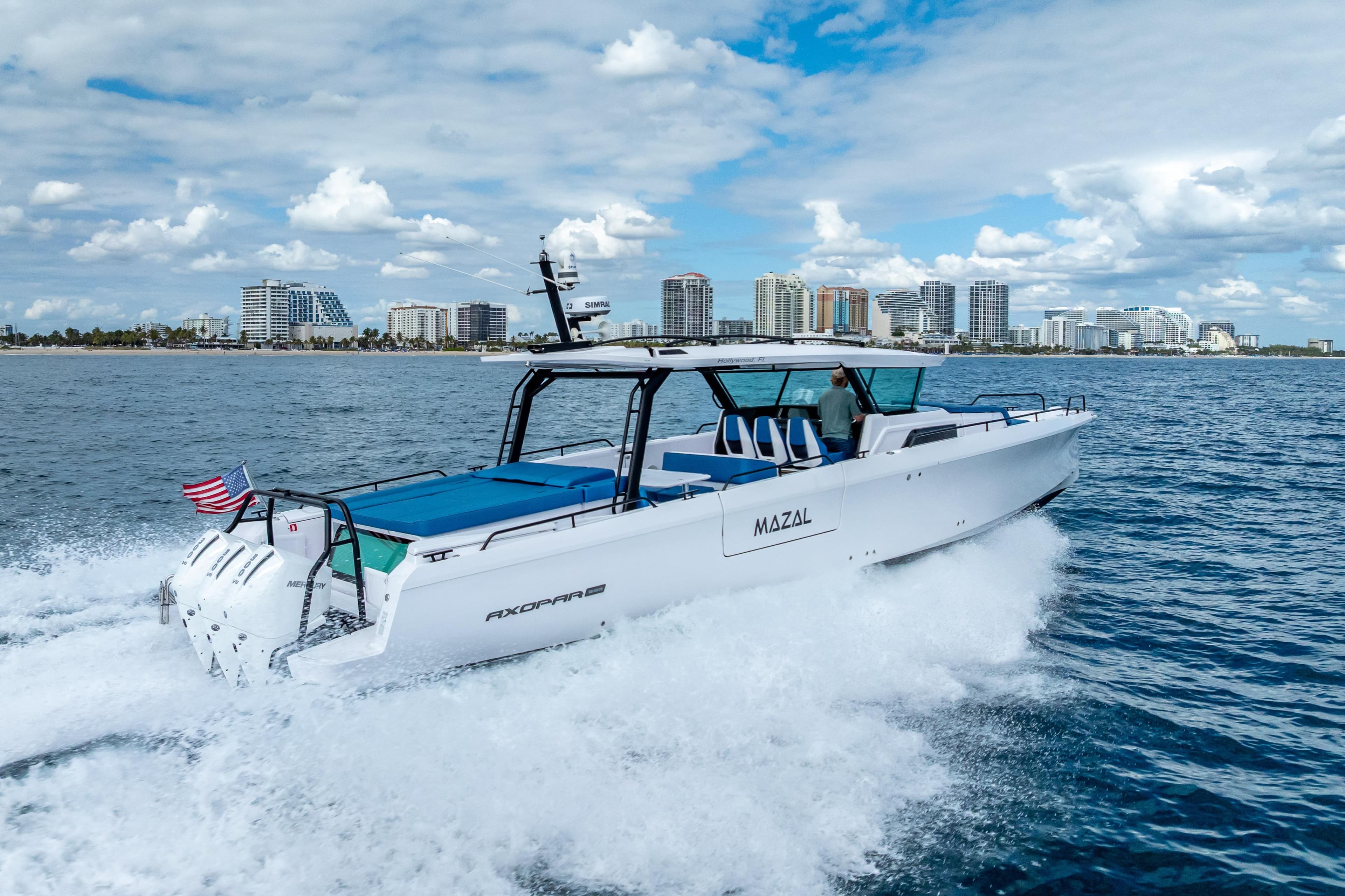 2025 Axopar 45 Cross Top cruising near city skyline on a sunny day.