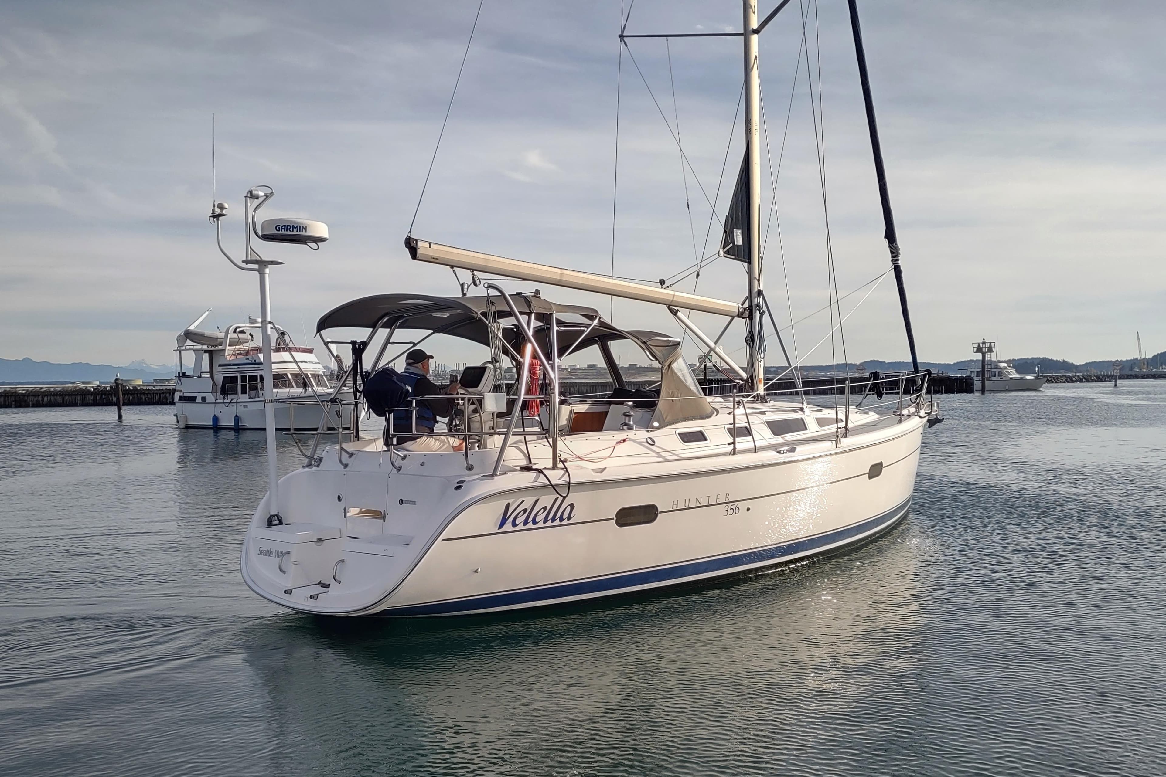 Sailboat "Velella," Hunter 356, 2003 model, cruising in calm waters near a marina.