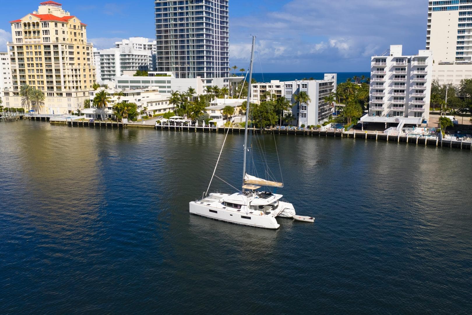 2021 Lagoon 52 F catamaran sailing near urban waterfront buildings.