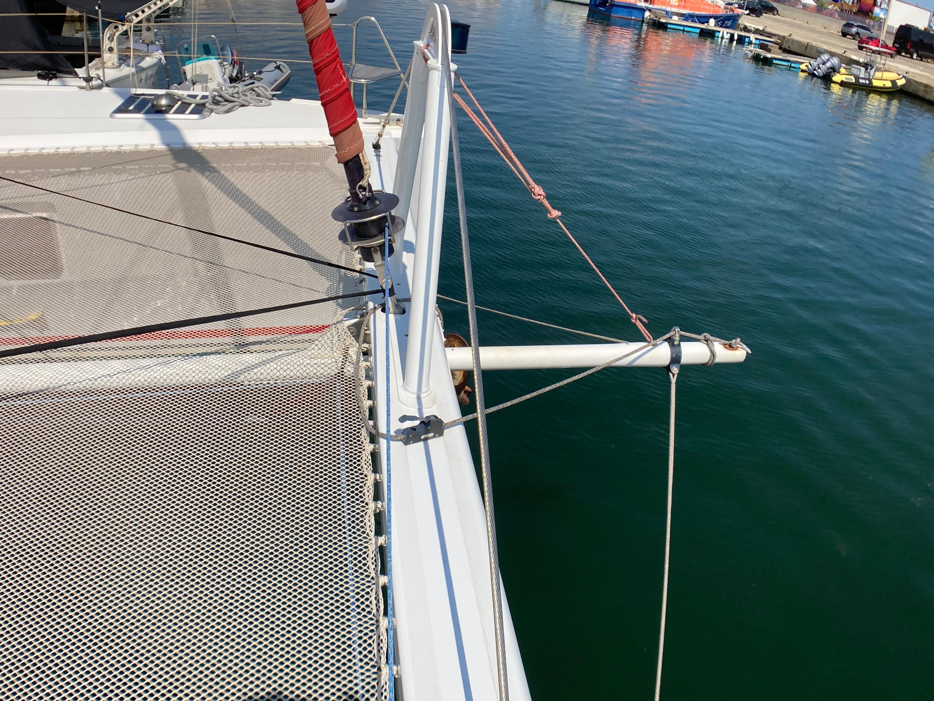 Catamaran deck with netting, Phisa XV 2010, docked in a marina.